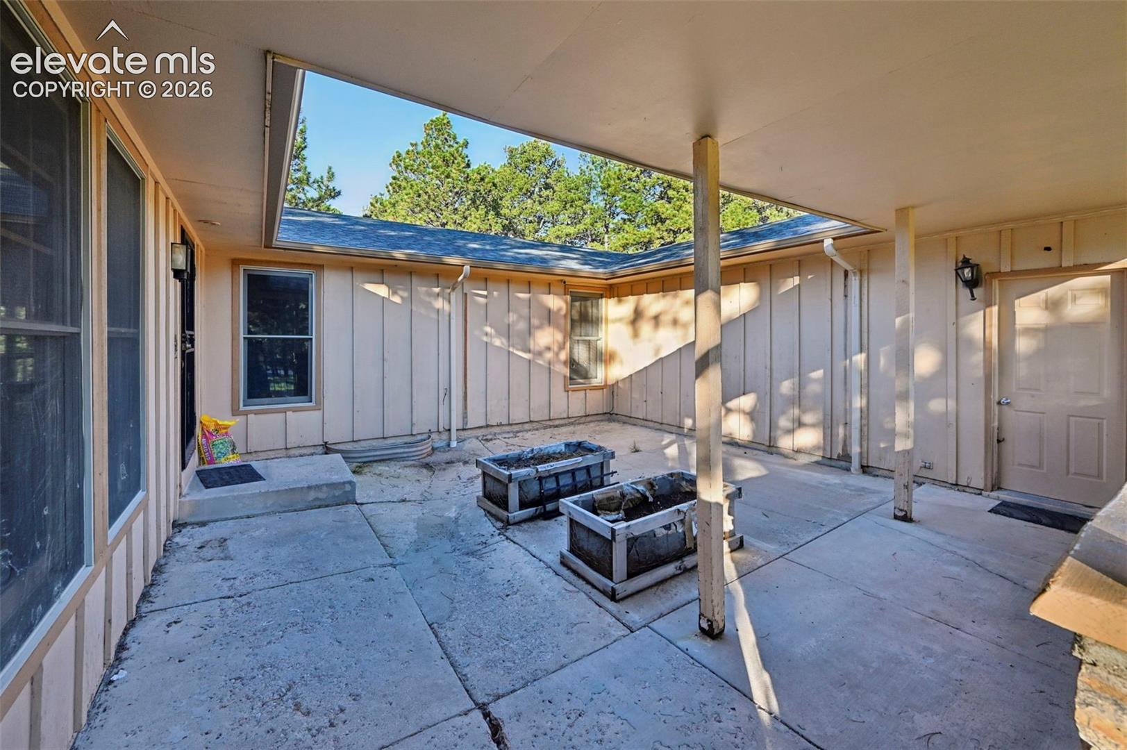 Covered patio featuring concrete flooring and exterior wall sconces