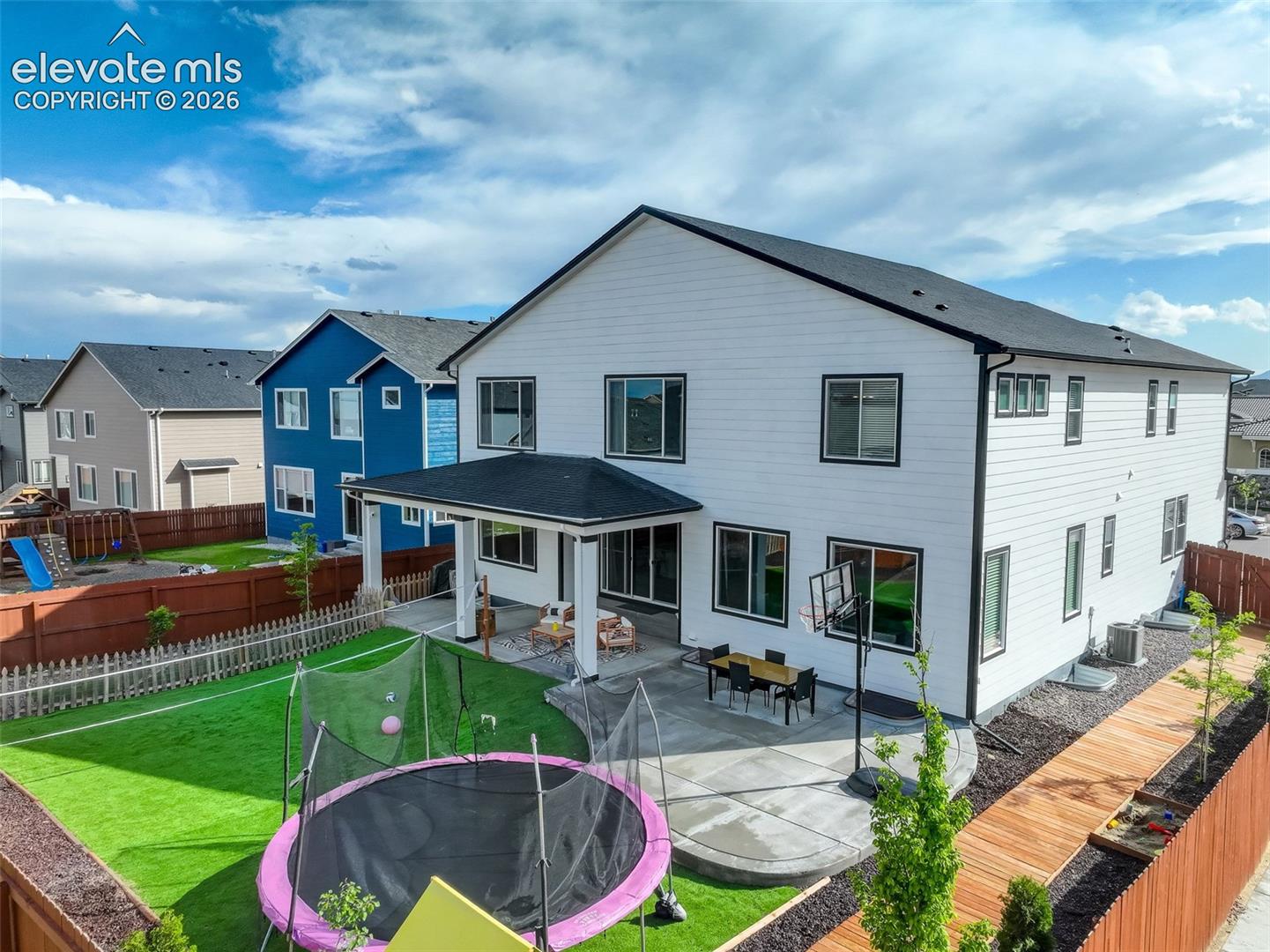 Back of house with a patio area, a trampoline, a fenced backyard, and a residential view