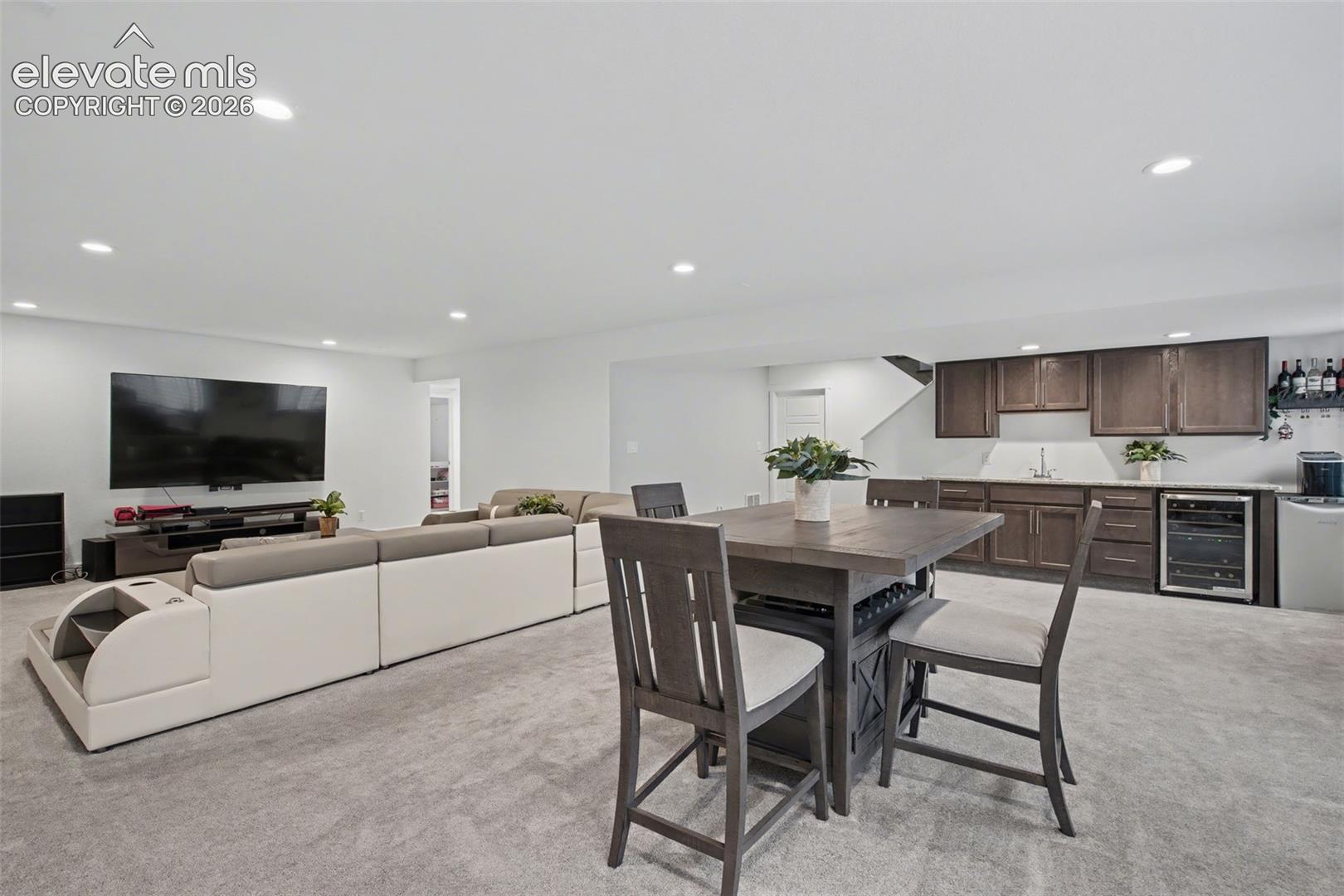 Dining space featuring light colored carpet, wet bar, wine cooler, and recessed lighting