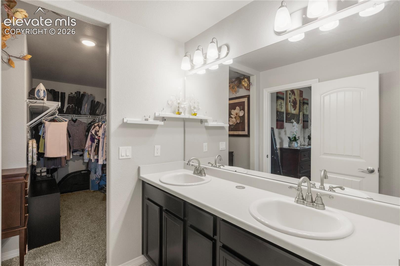 Dual vanity with white countertop, chrome faucets, and dark wood-finish cabinetry
