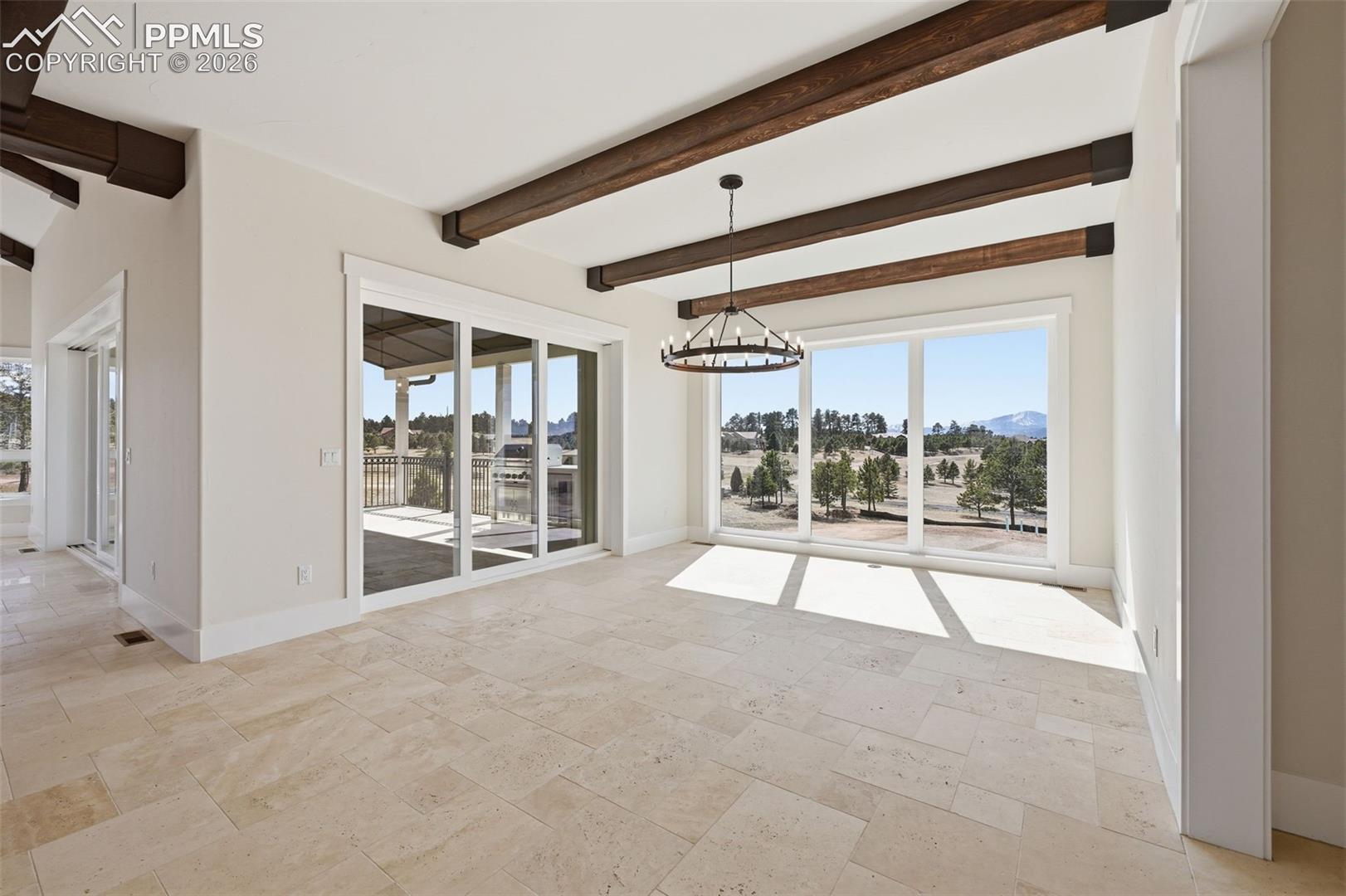 Dining Room with suspended lighting, beamed ceiling, stone tile flooring, and a mountain view. Accesses patio (to left.)
