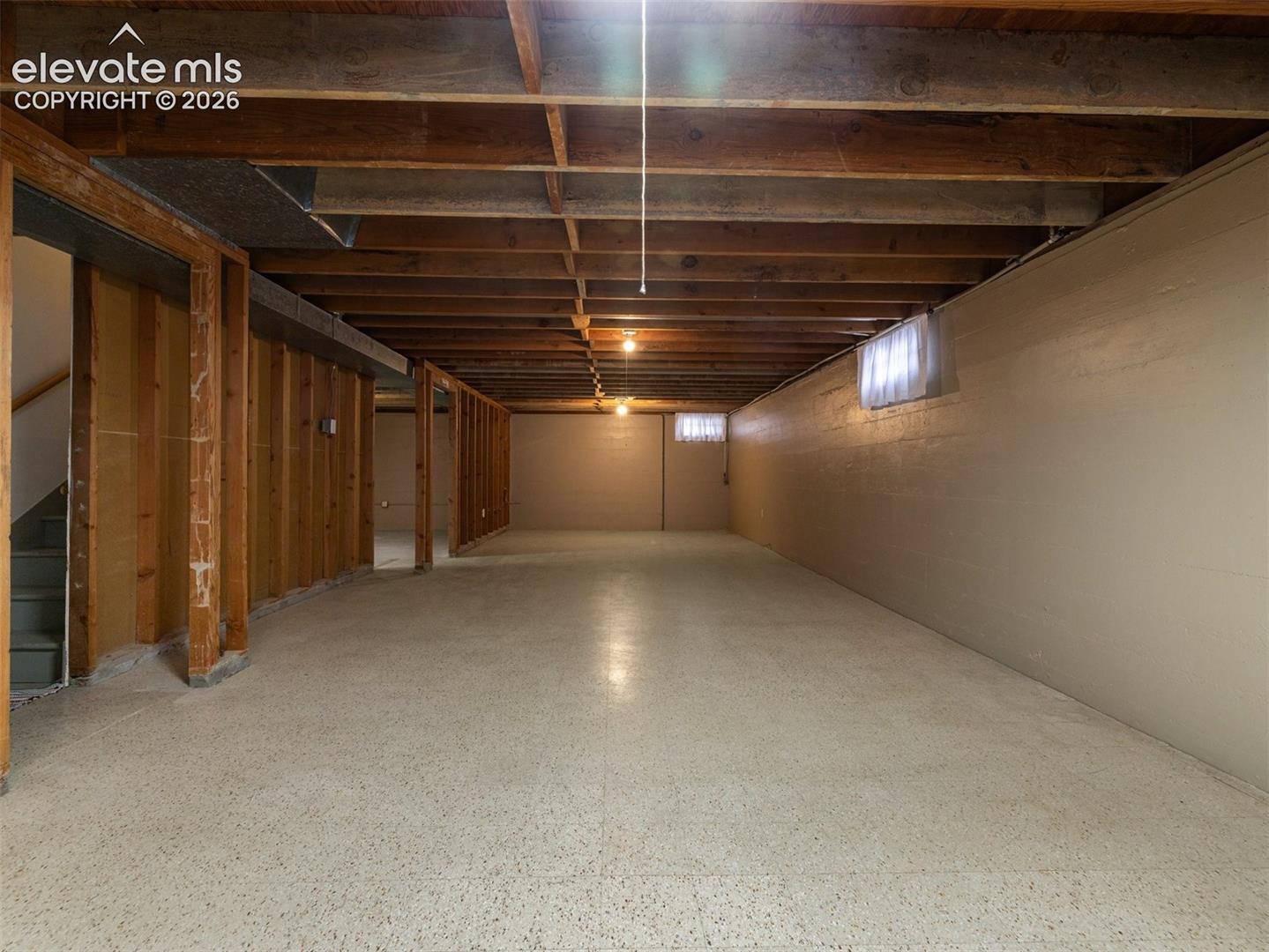 Unfinished basement featuring exposed wood joists, concrete flooring, and multiple framed interior walls