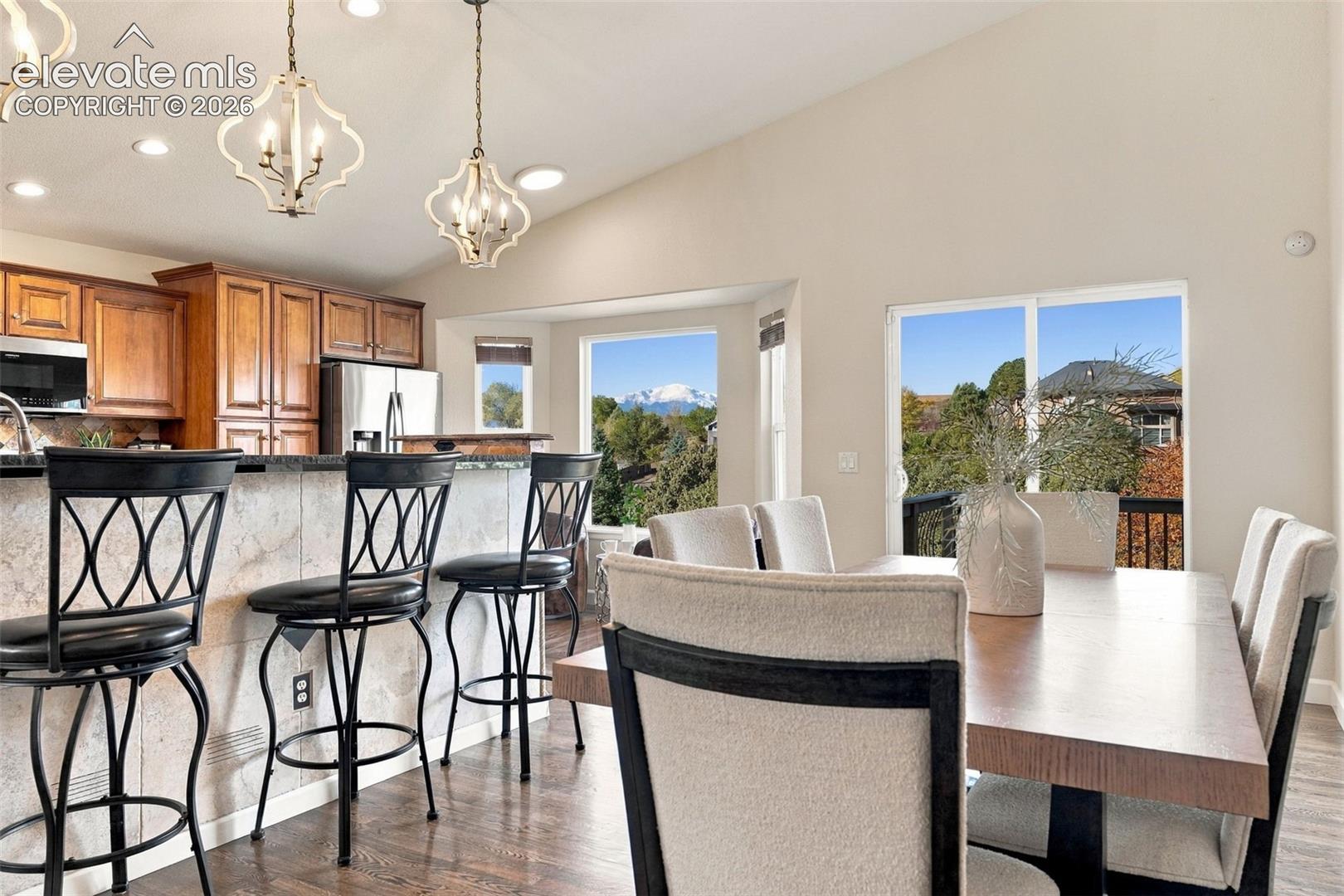 Vaulted ceilings, wood-finish flooring, custom wood cabinetry, decorative pendant lighting, and mountain scenery