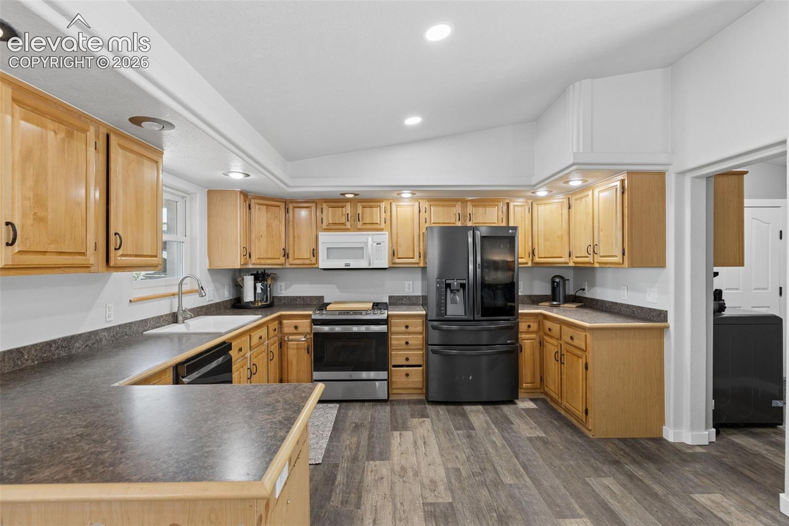 Kitchen featuring wood cabinetry, laminate countertops, recessed lighting, and wood-finish flooring