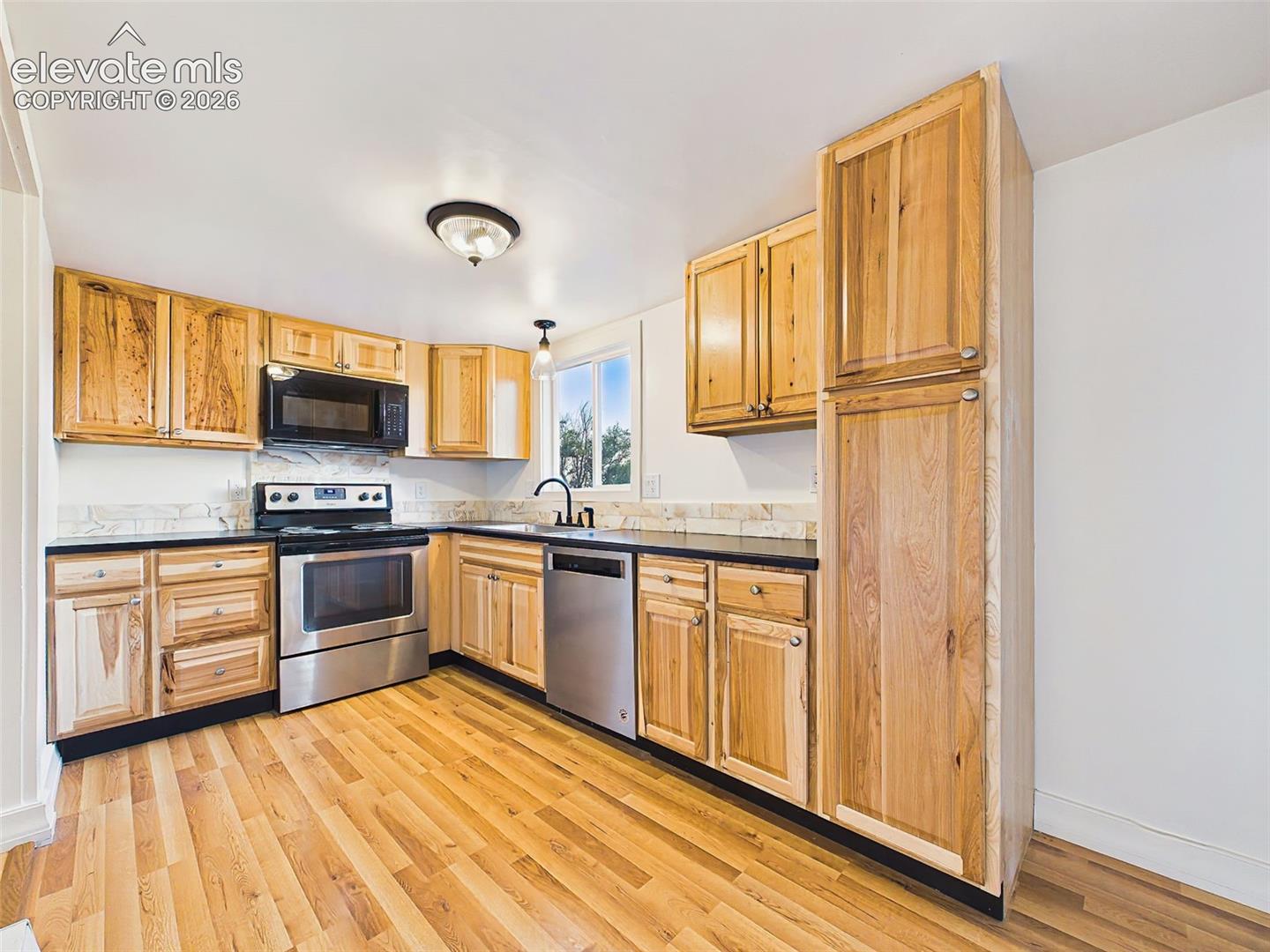 Kitchen – Completely remodeled kitchen featuring custom wood cabinetry, updated countertops, stainless steel appliances, and durable laminate flooring.