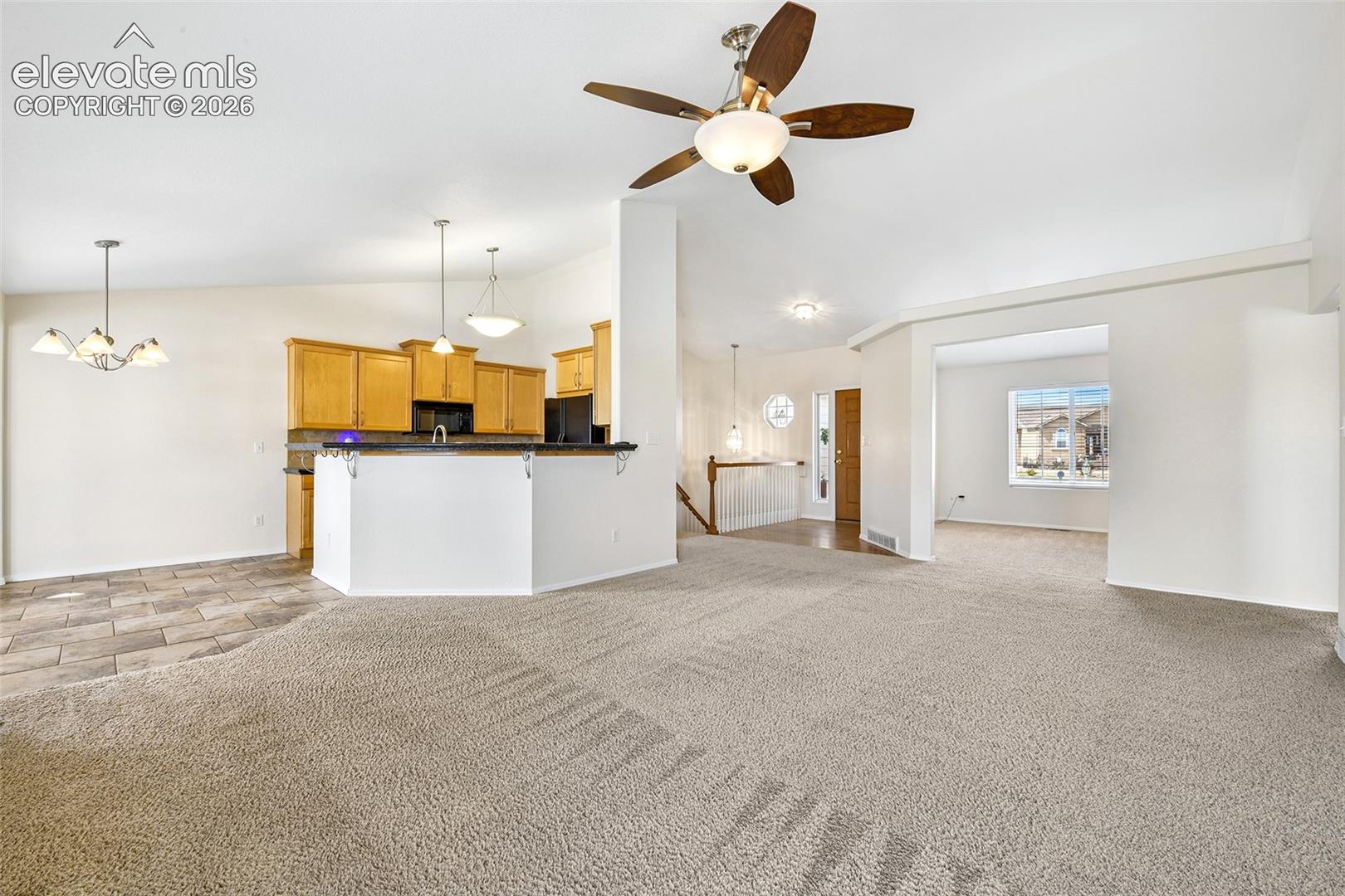 Open-concept living area with carpet flooring and a ceiling fan