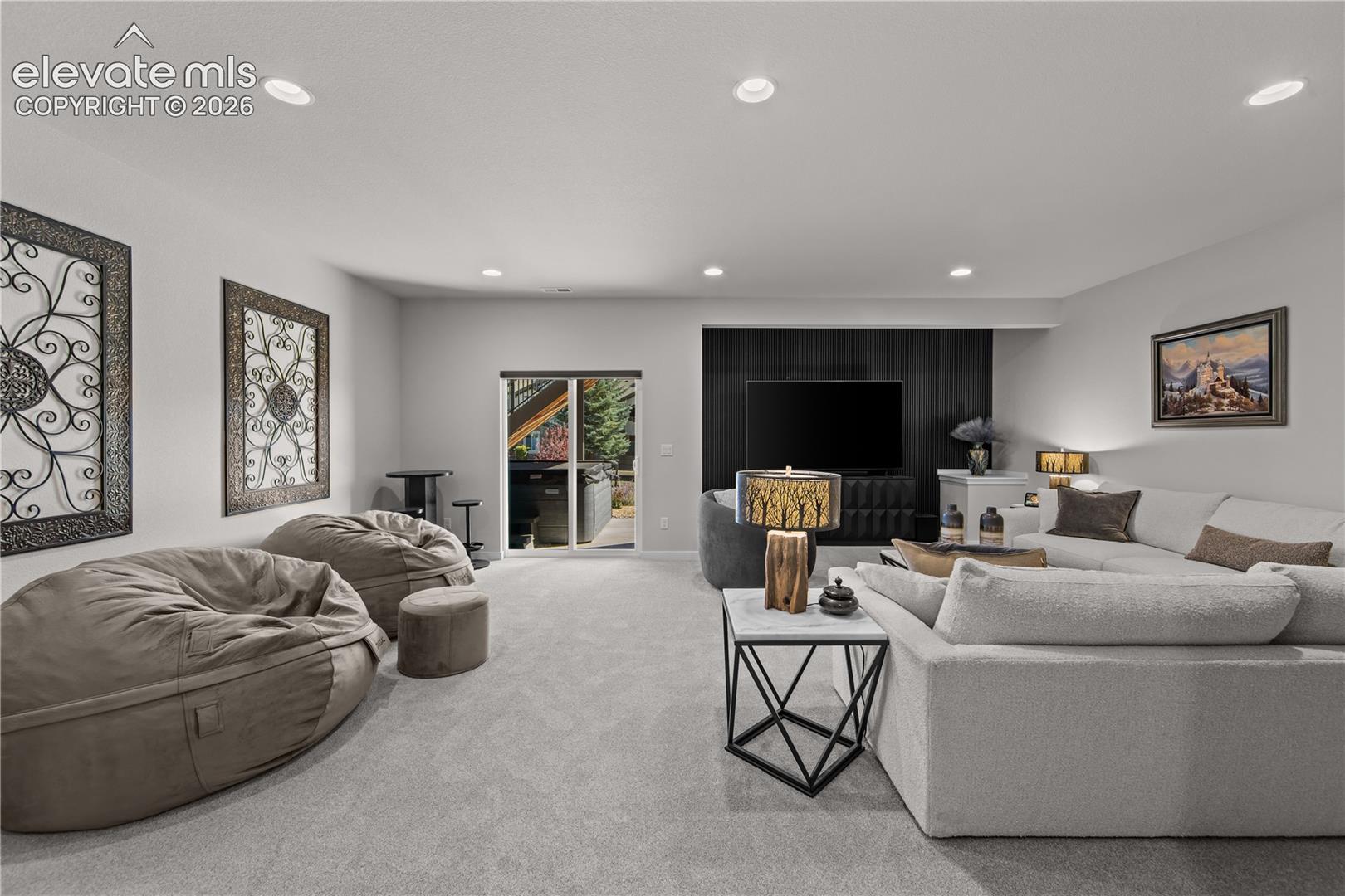 Neutral-toned carpeted flooring, recessed lighting, and a black paneled accent wall featuring a wall-mounted television
