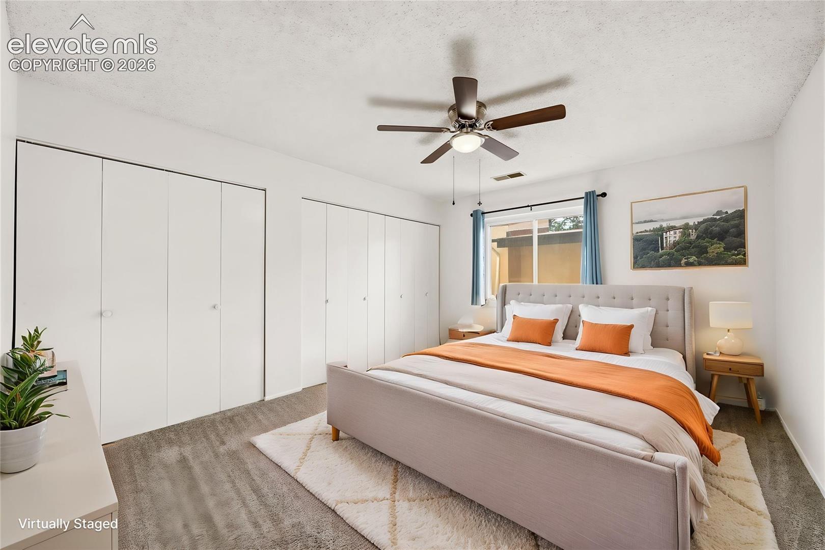 Bedroom featuring dual floor-to-ceiling closets, wall-to-wall carpeting, and a ceiling fan with integrated lighting