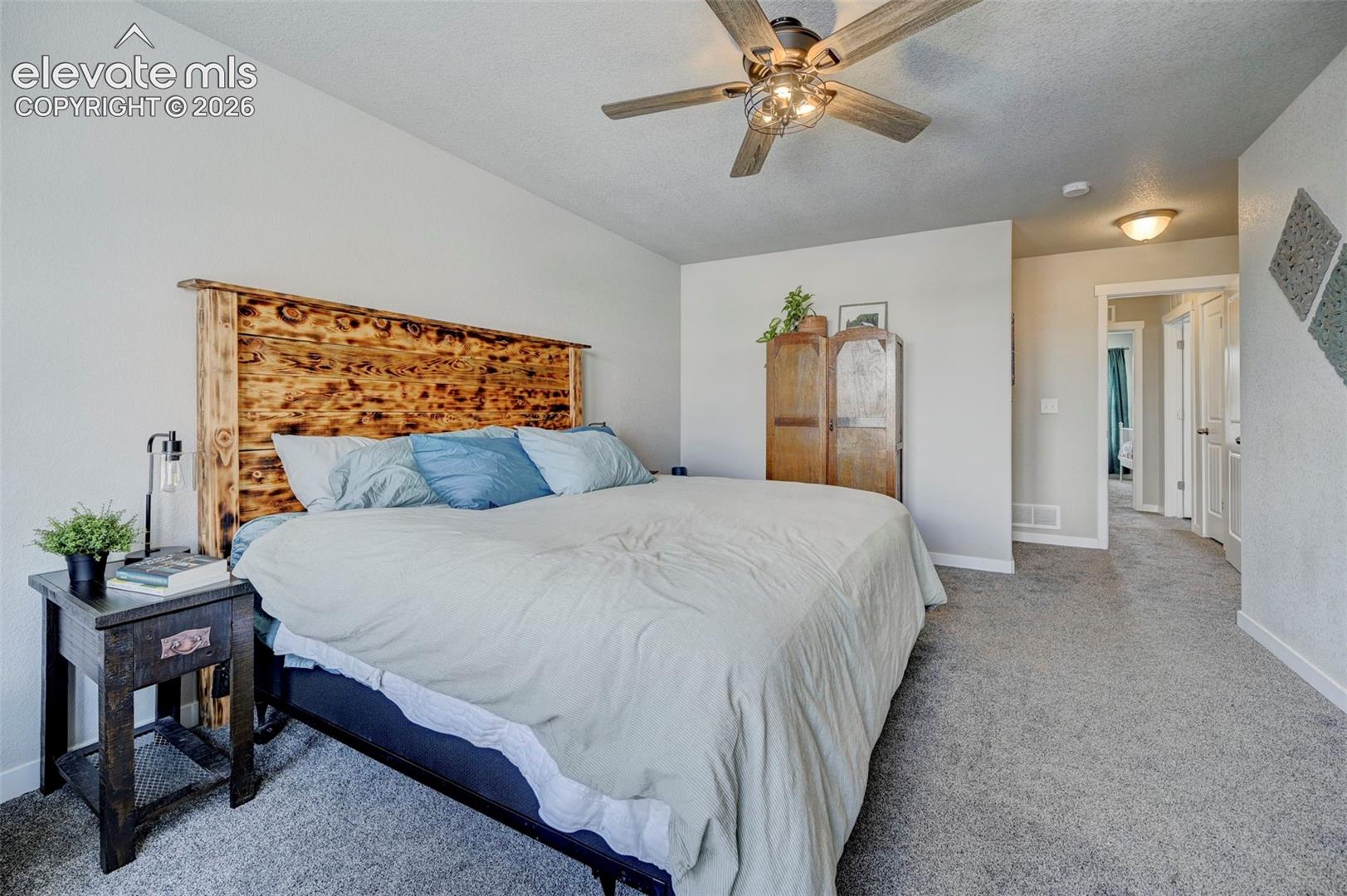 Neutral wall-to-wall carpeting, ceiling fan with integrated lighting, and wooden-framed doorway entries