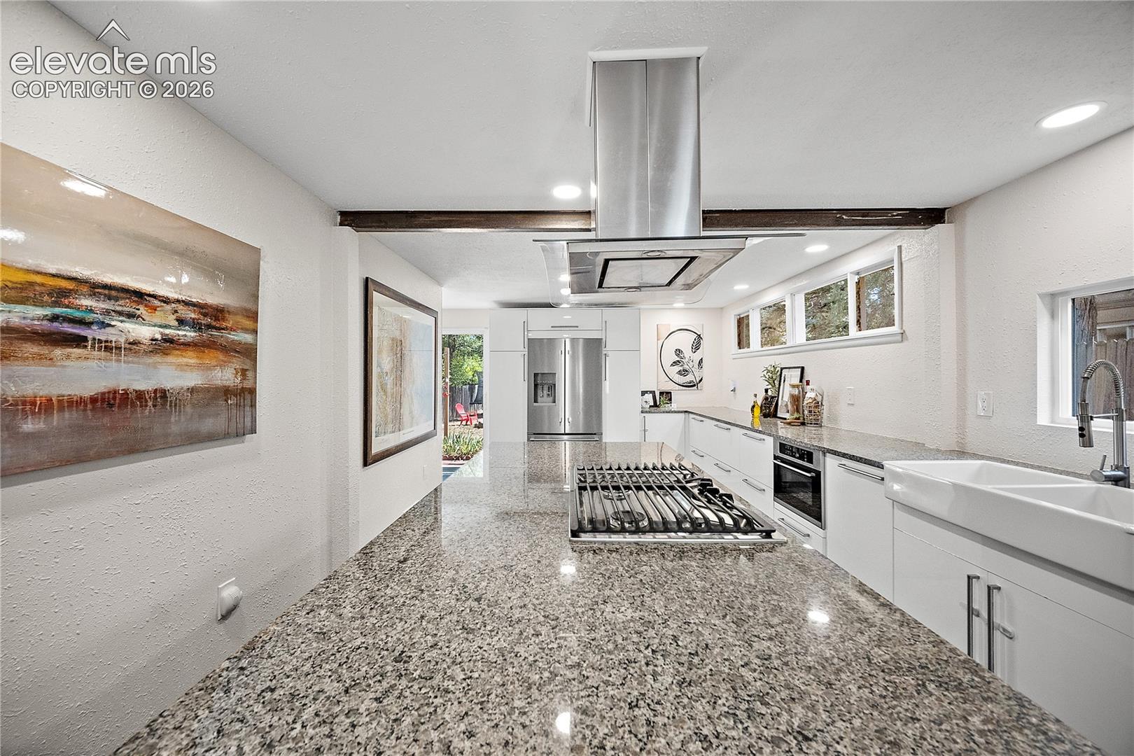 Modern kitchen featuring granite countertops, wood-finish flooring, and a stainless steel island range hood