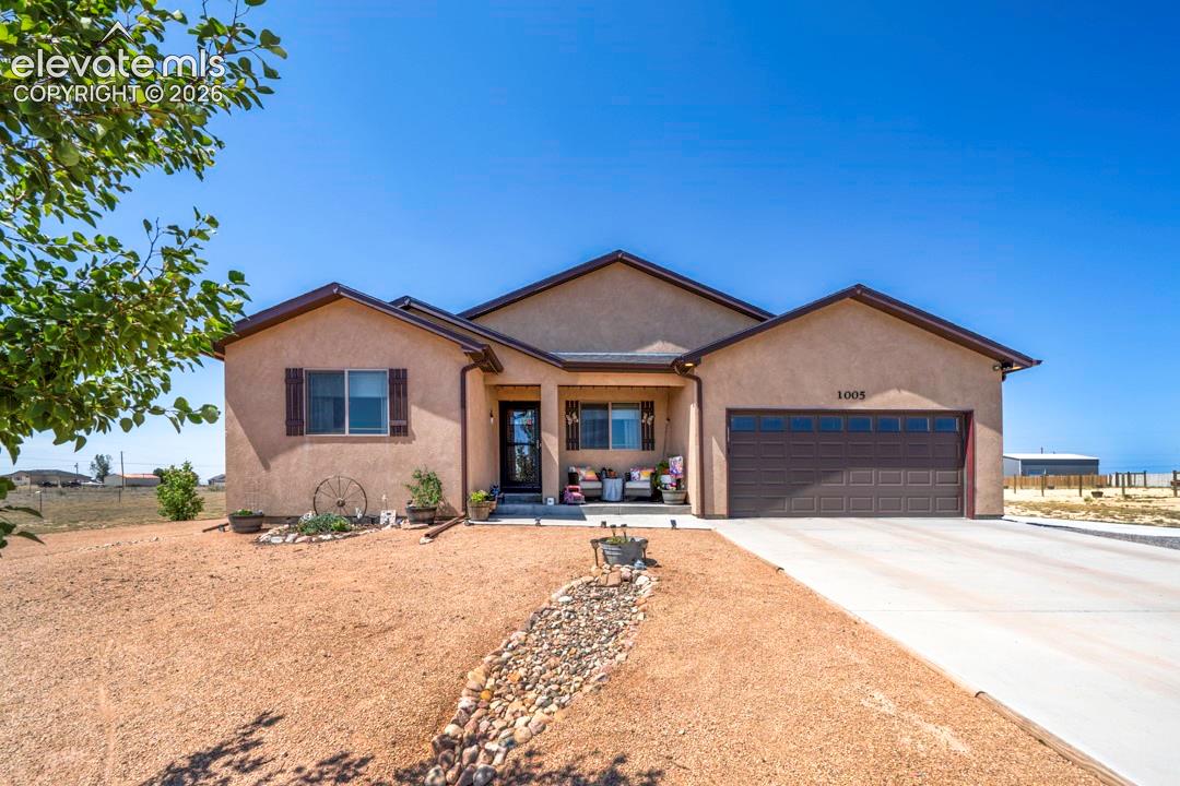 Stucco exterior with a covered entry, attached garage, and concrete driveway