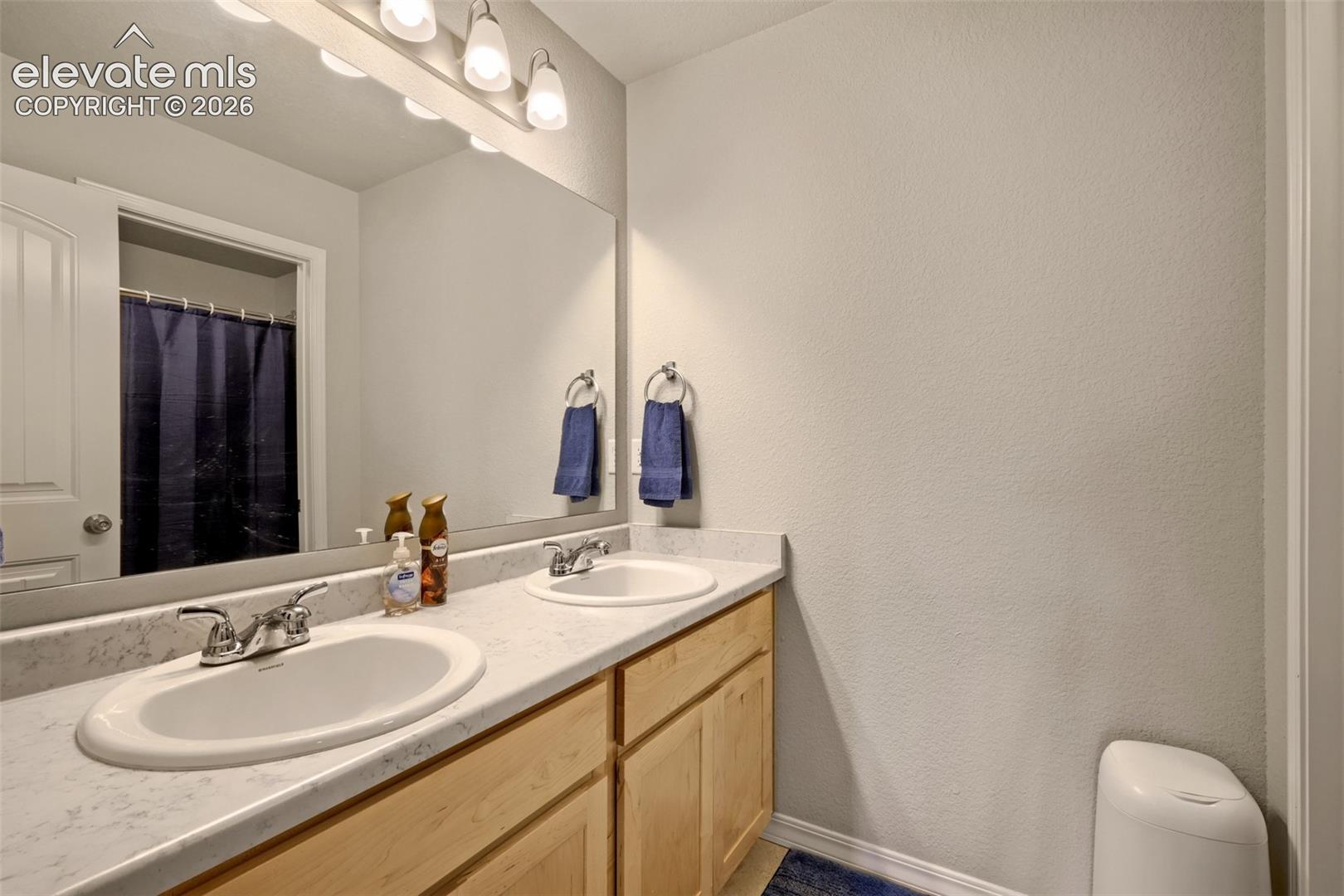 Bathroom featuring a dual sink vanity with integrated oval basins and chrome fixtures, set against a light-colored countertop