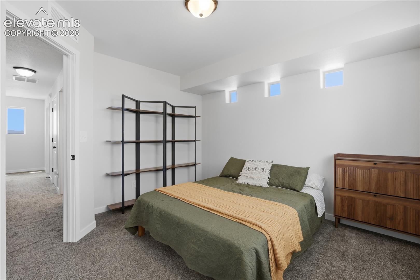 Carpeted bedroom featuring white walls and multiple transom windows