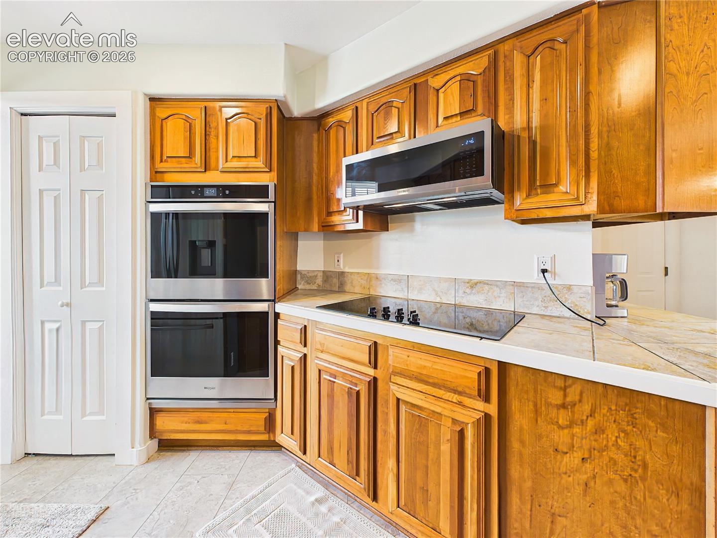Stainless steel double wall ovens, modern cooktop, and plentiful cabinetry make this kitchen well-equipped for everyday cooking and special occasions.
