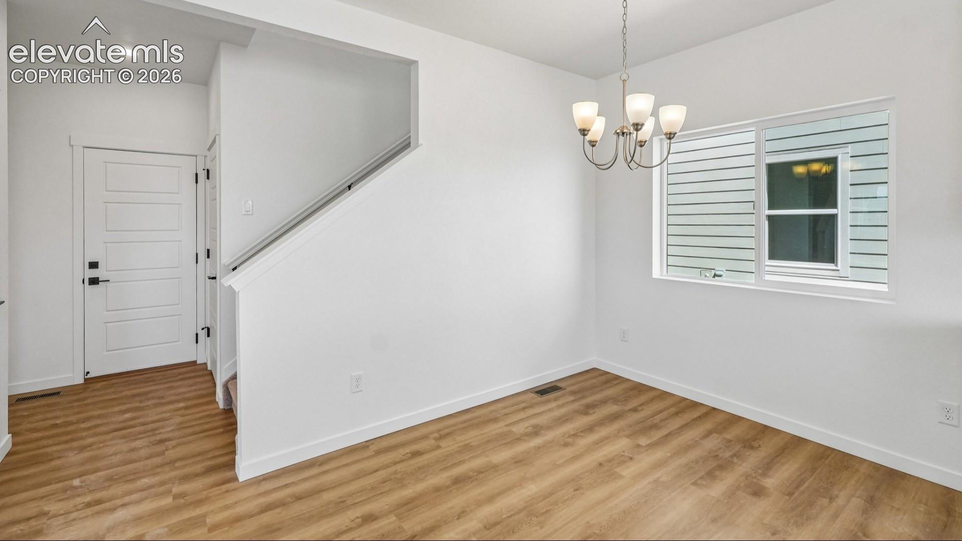 Entry featuring a five-panel door with matte black hardware, wood-finish flooring, a multi-light chandelier, and a horizontal sliding window