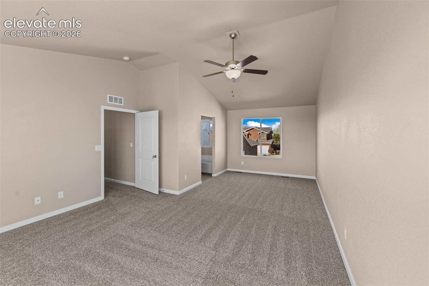 Vaulted ceilings, neutral carpeting, and a polished nickel ceiling fan with integrated lighting