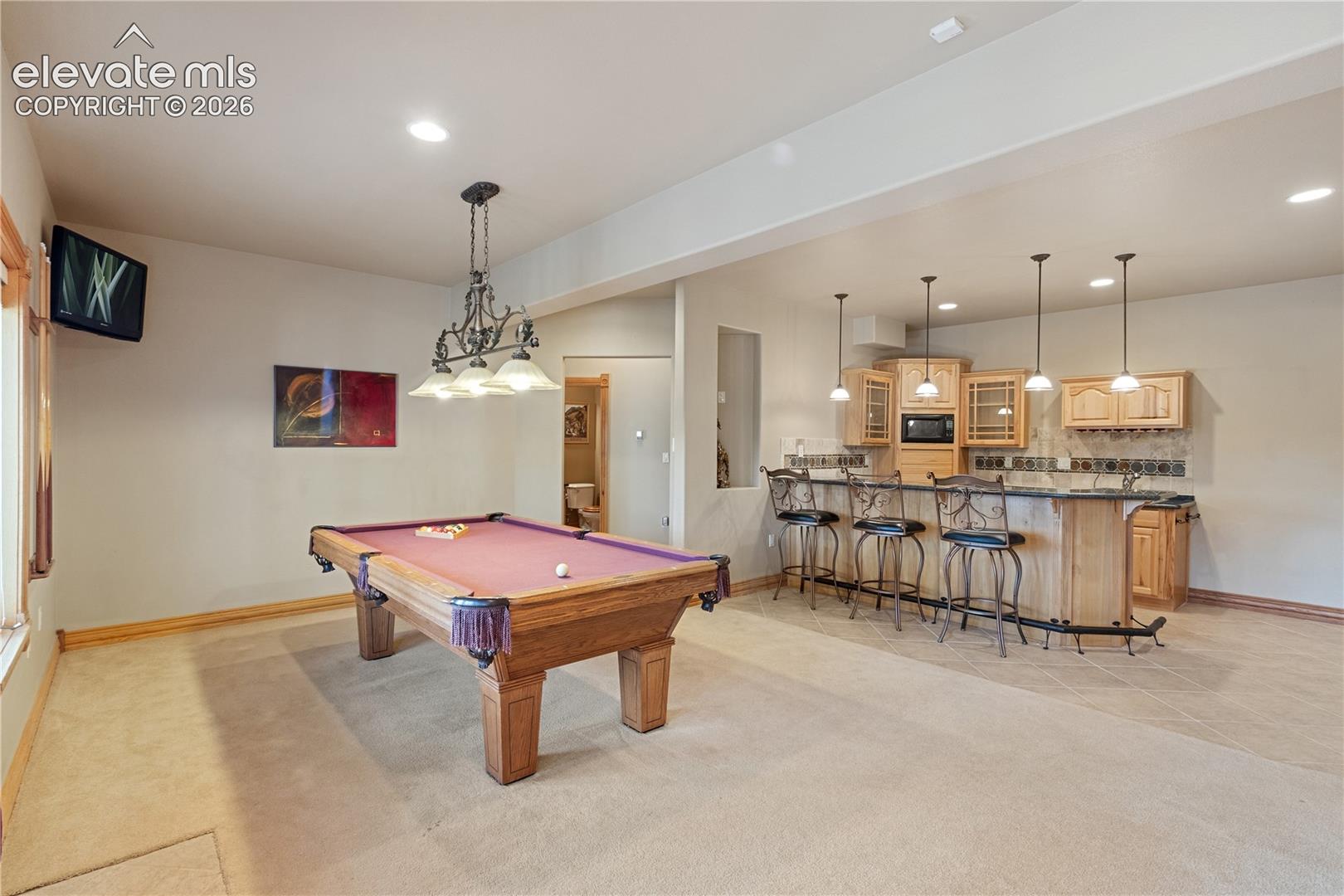 Downstairs game room looking from fireplace toward wet bar and bedrooms