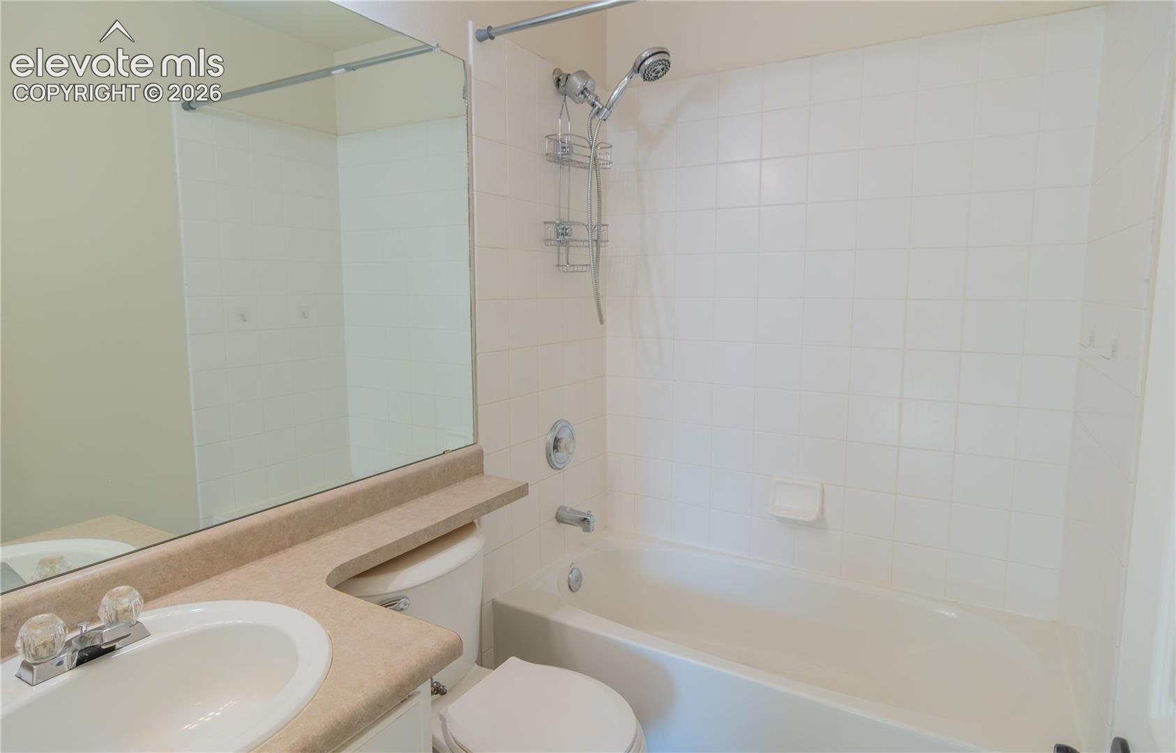 Full bathroom featuring a tub/shower combination, tiled surround, and spacious vanity counter.