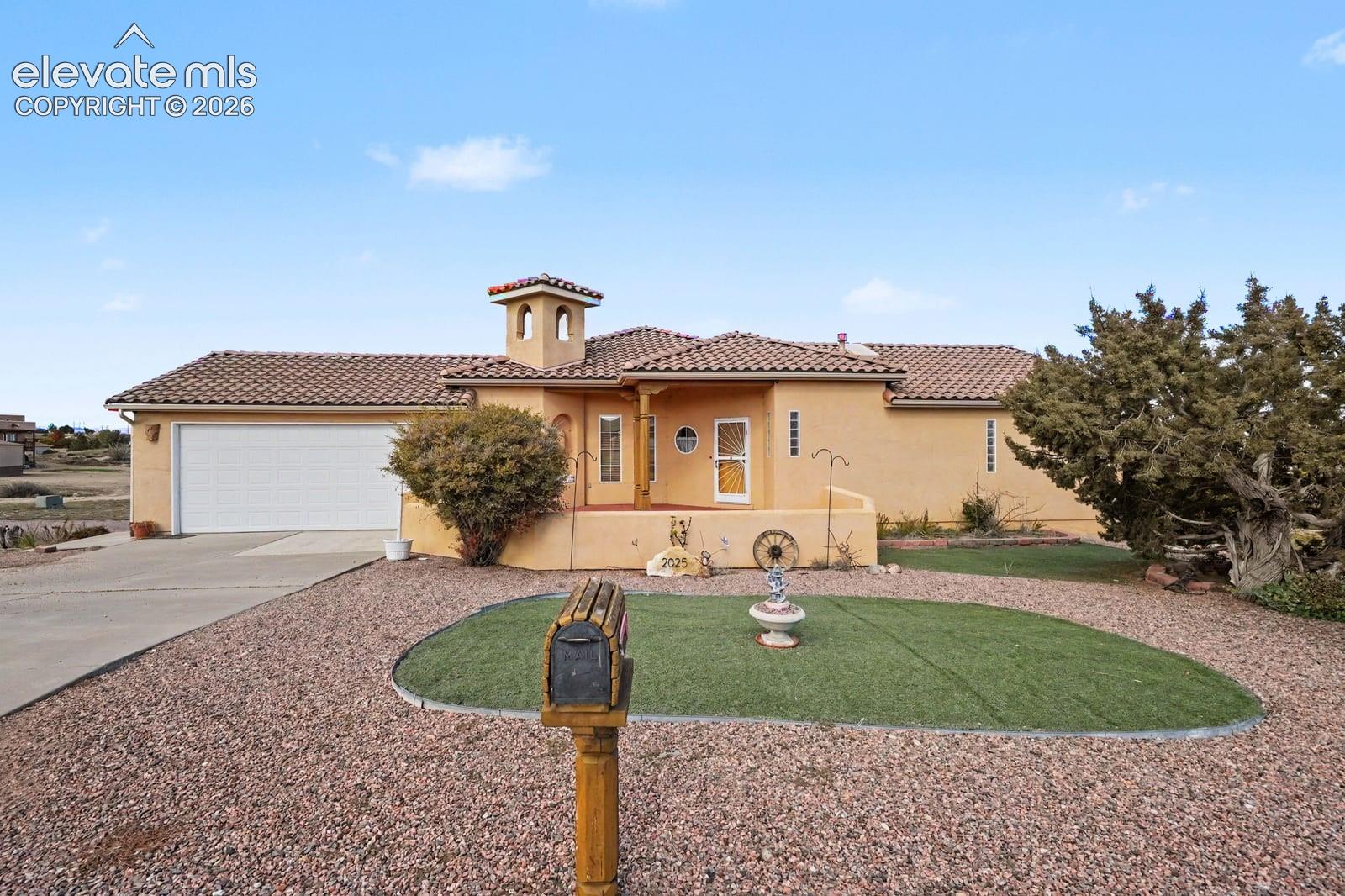 Single-story stucco exterior featuring a tile roof, cupola, covered entryway, and attached two-car garage