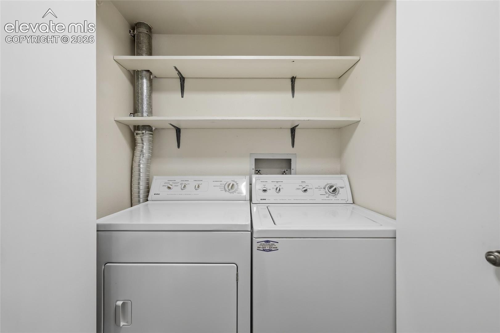 Laundry alcove featuring two built-in white storage shelves and dedicated appliance hookups