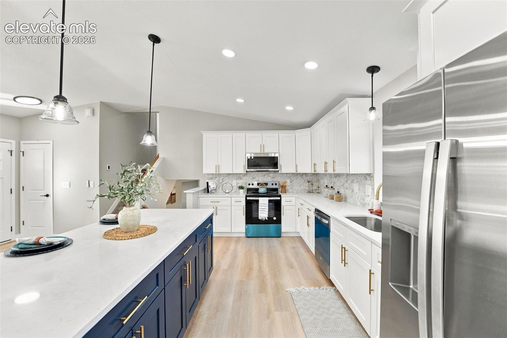 Kitchen featuring white upper cabinetry, a navy blue island base, light-toned wood-finish flooring, recessed lighting, and a stone-patterned backsplash