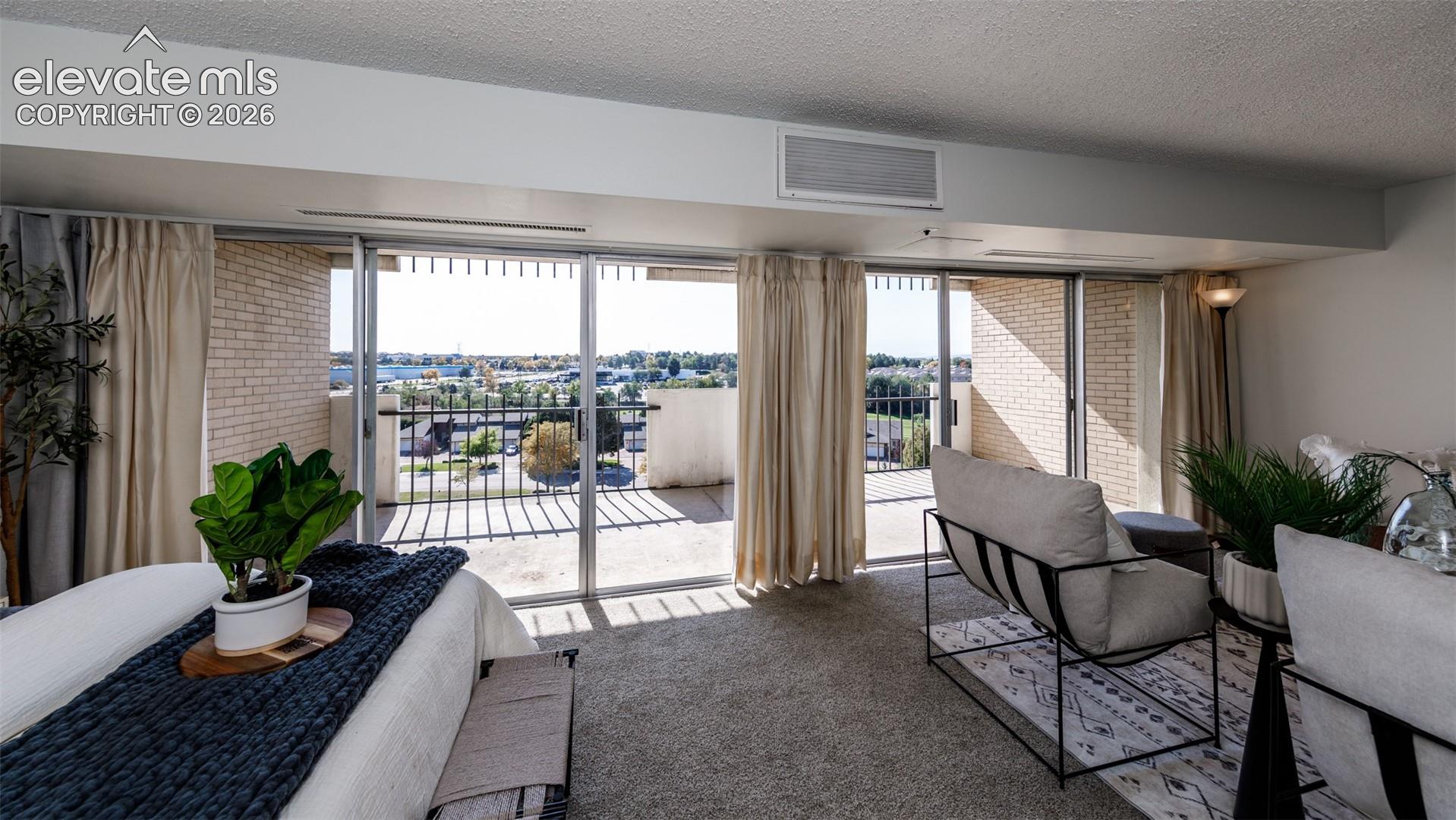 Floor-to-ceiling sliding glass doors opening to a private exterior balcony featuring brick accents and metal railing