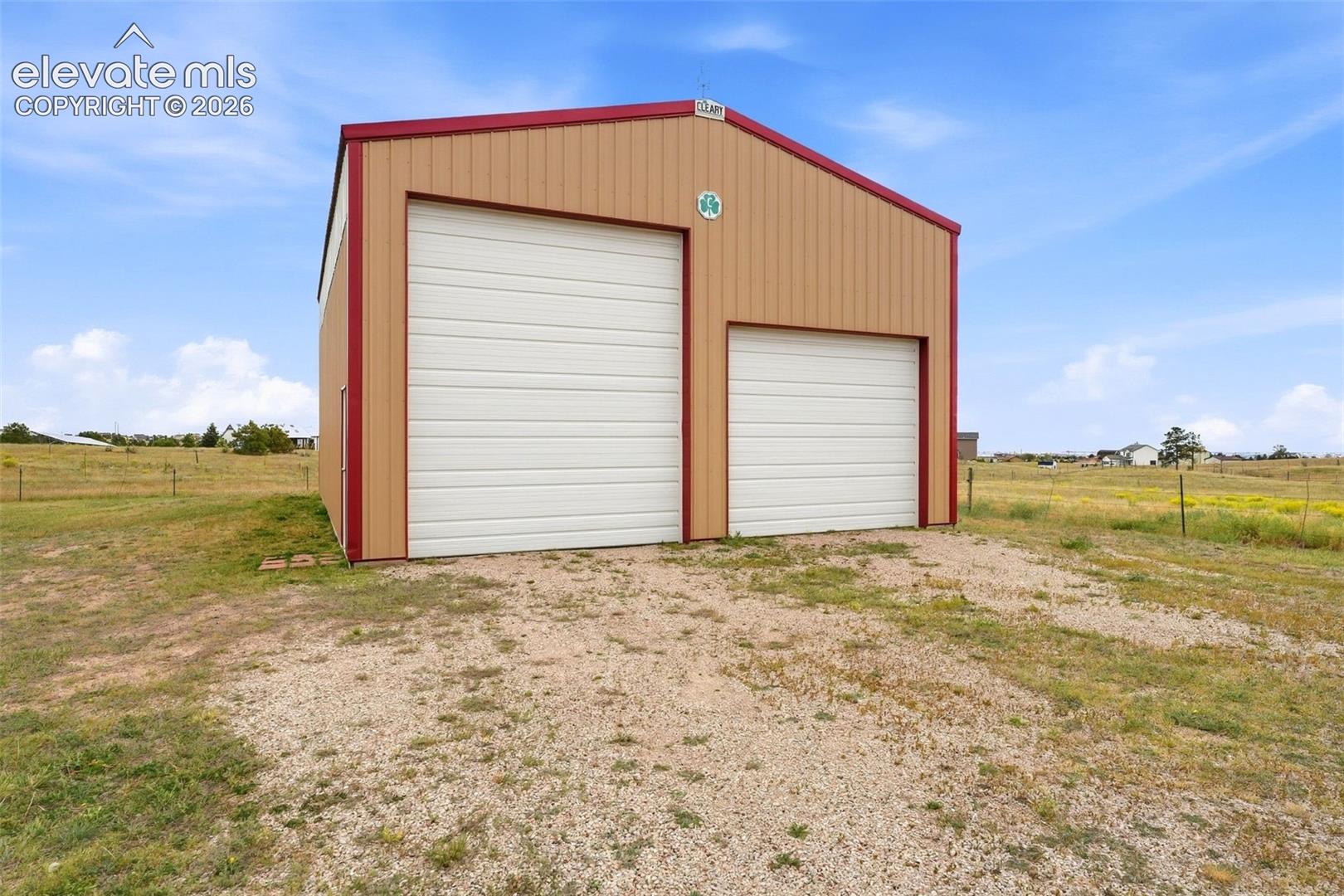 Metal building with a gambrel roof and two white roll-up doors