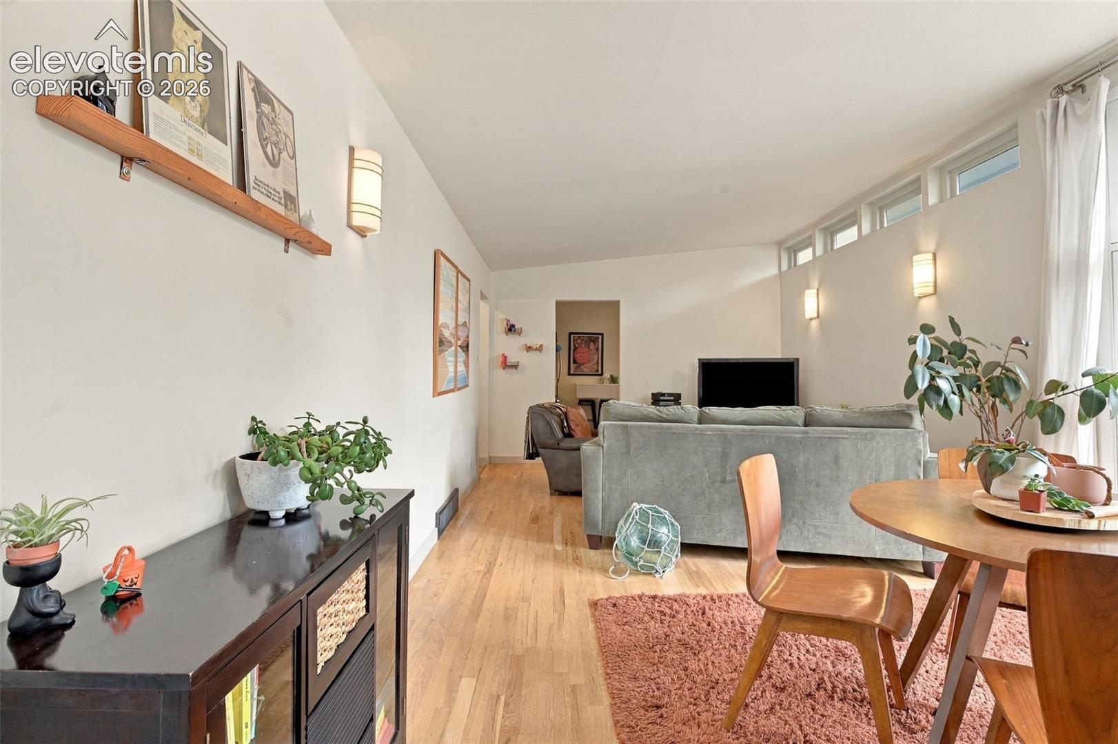 Living area featuring wood-finish flooring, a series of clerestory windows, and wall-mounted light fixtures