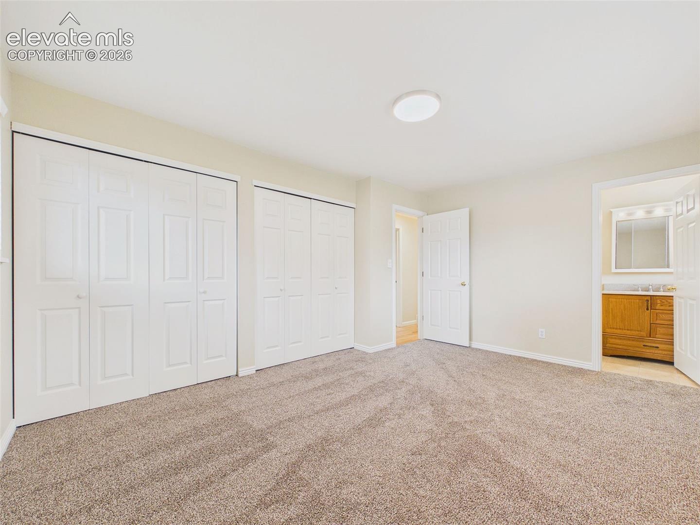 Another view of the generously sized primary bedroom highlights the comfortable layout, abundant natural light, and ample wall space for furniture placement.