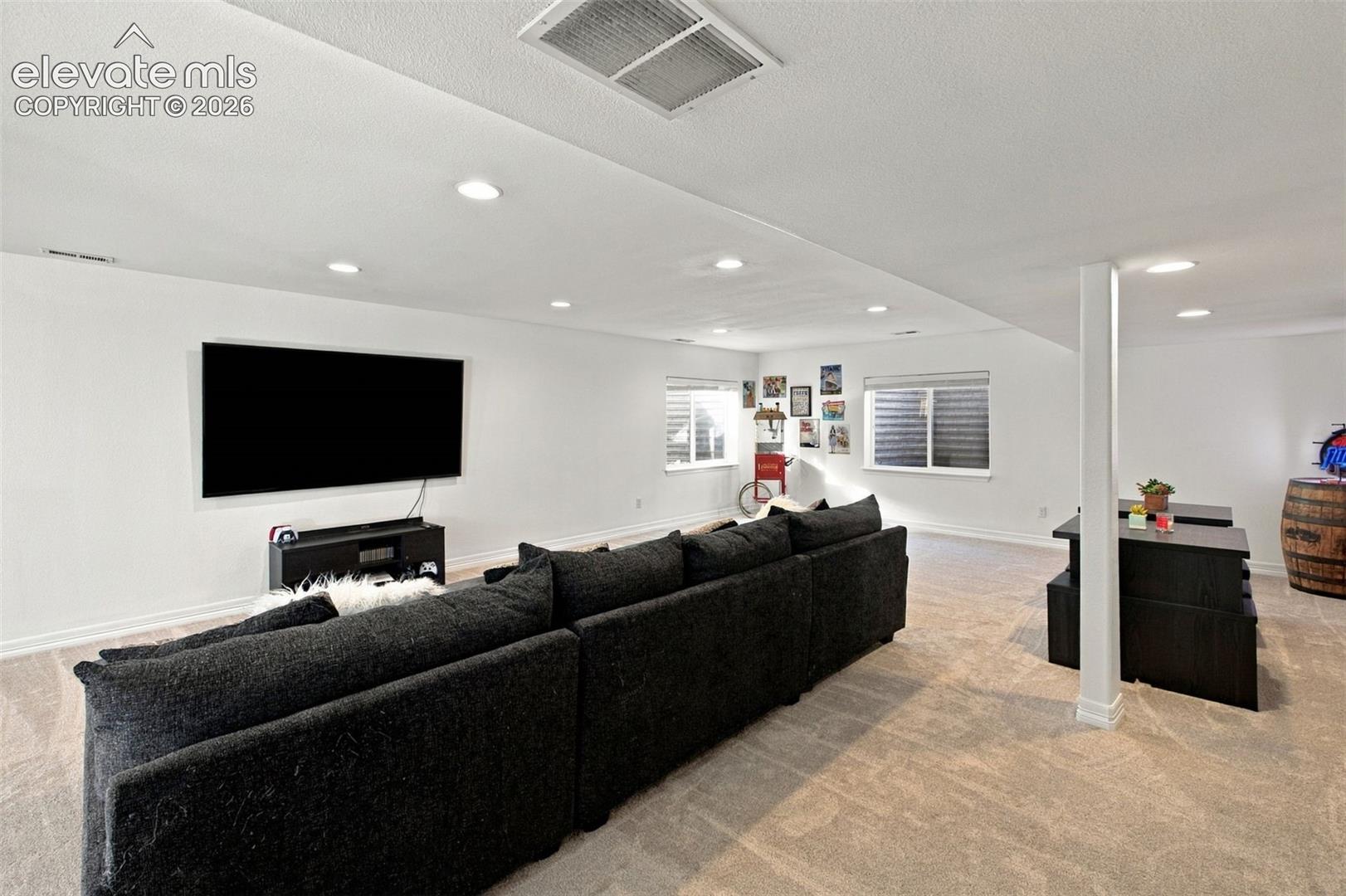 Open-concept interior featuring neutral carpeting, recessed lighting, and horizontal windows