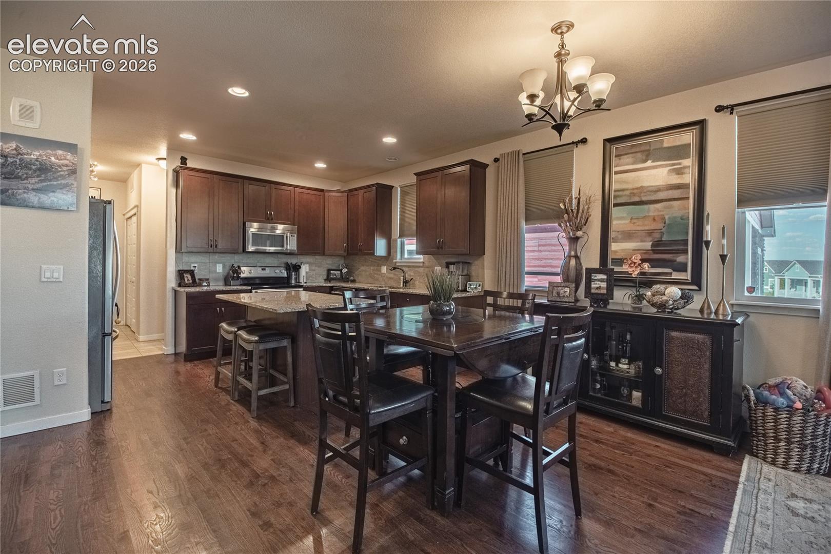 Kitchen featuring dark wood cabinetry, stone-surface island countertop, recessed lighting, and wood-finish flooring