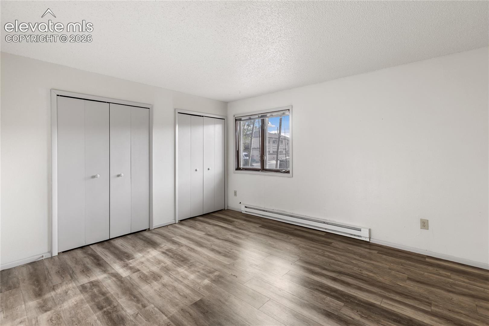 Room featuring wood-finish flooring, white walls, and a textured ceiling