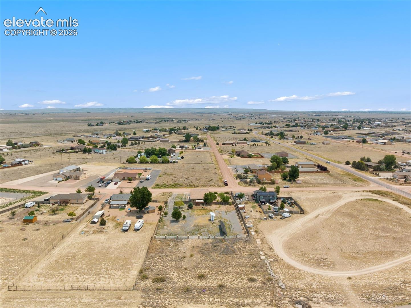 Aerial perspective of expansive residential lot featuring cleared terrain, defined property boundaries, and gravel-surfaced driveway
