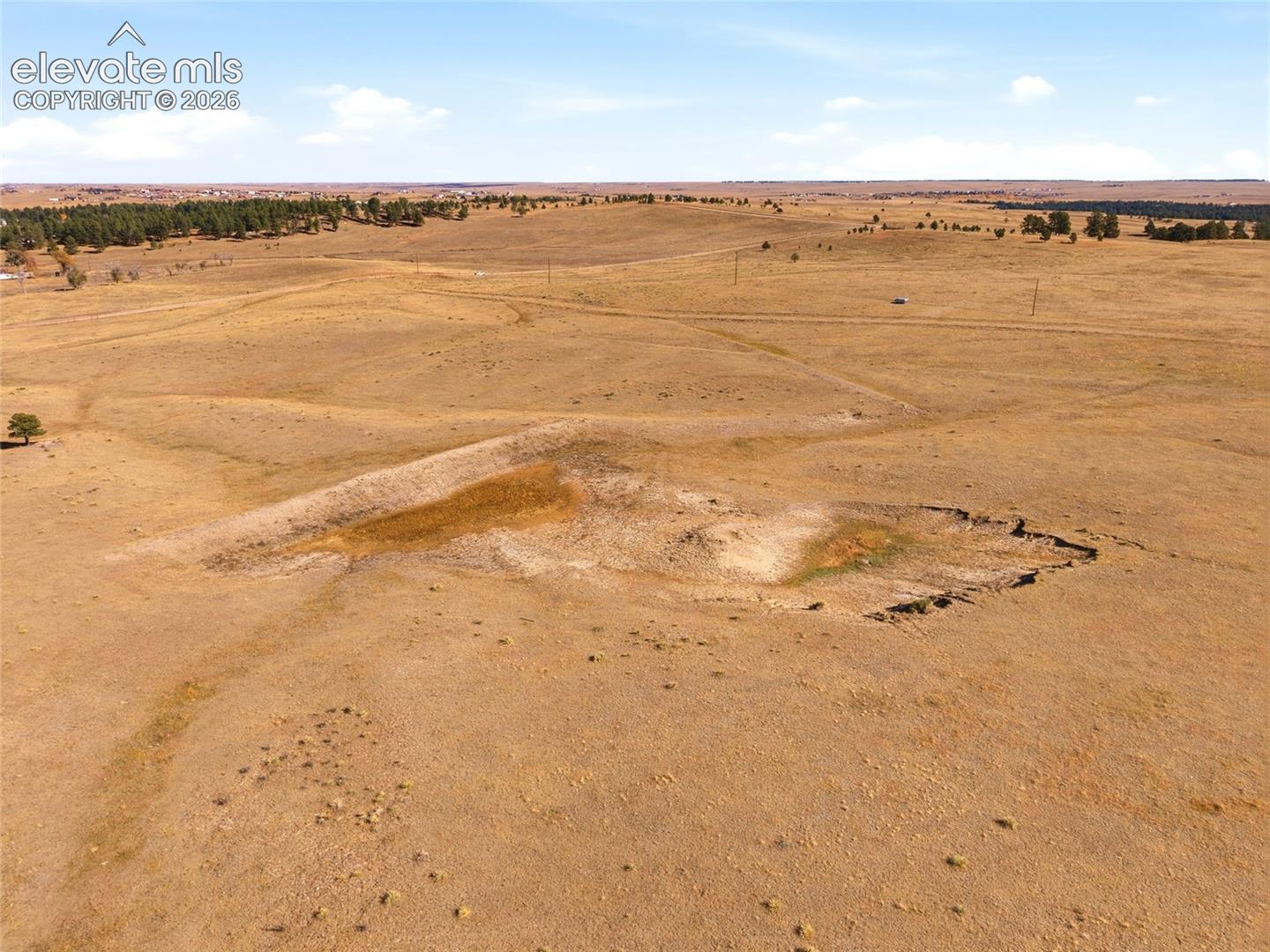 Expansive acreage featuring rolling topography, natural earthen basins, and scattered mature tree clusters