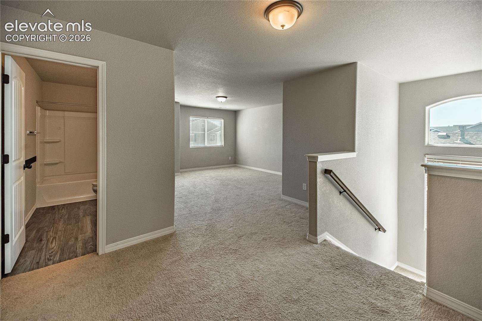 Neutral-toned carpeting throughout, white trim, and a white interior door with black hardware