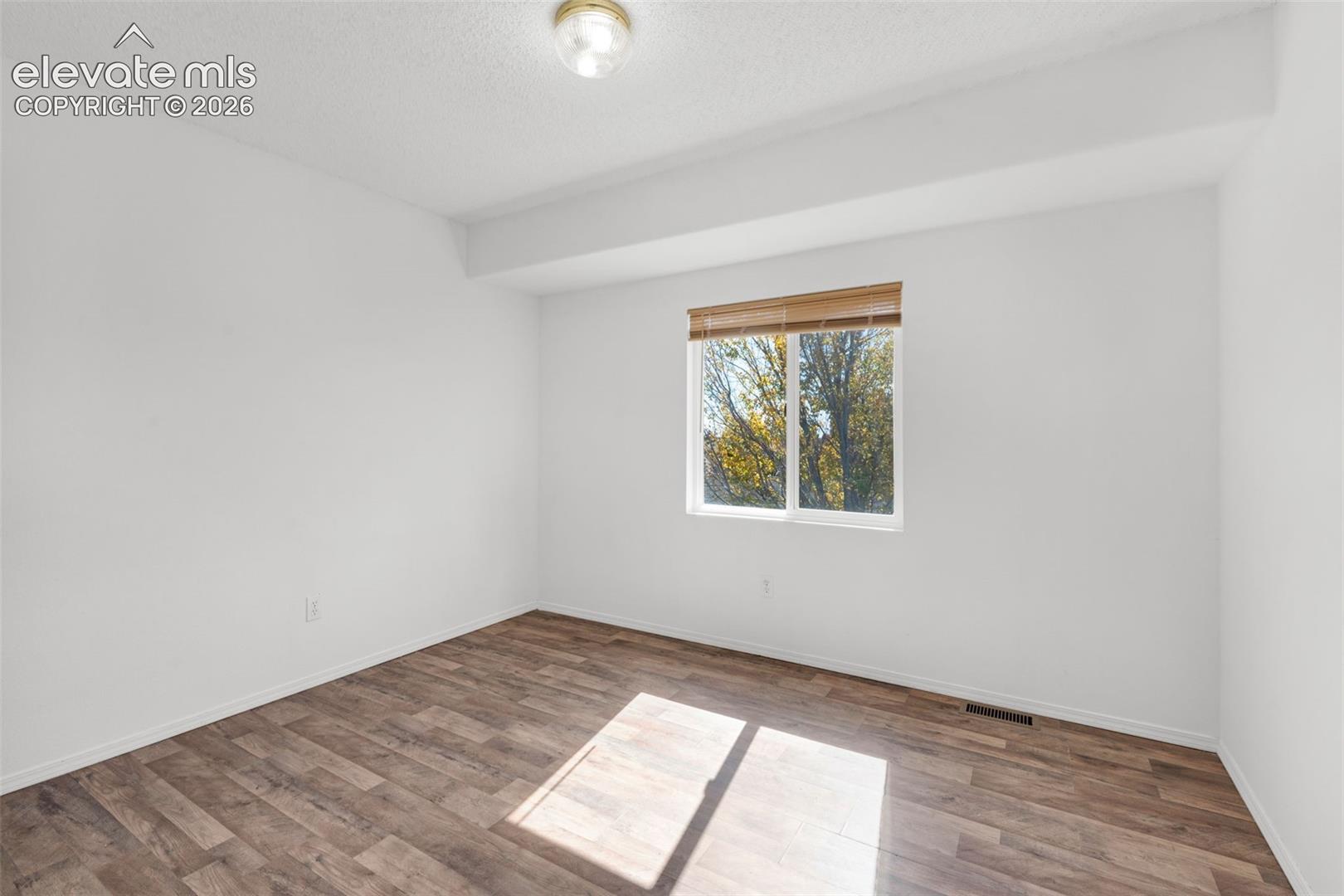 Wood-finish flooring, single window with blinds, and flush mount ceiling light