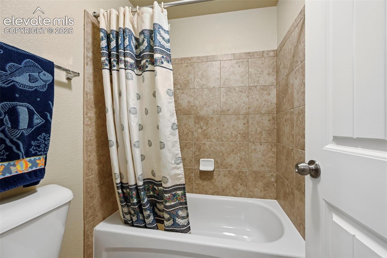Baement Bath with Full-sized bathtub with tiled surround featuring a neutral tone