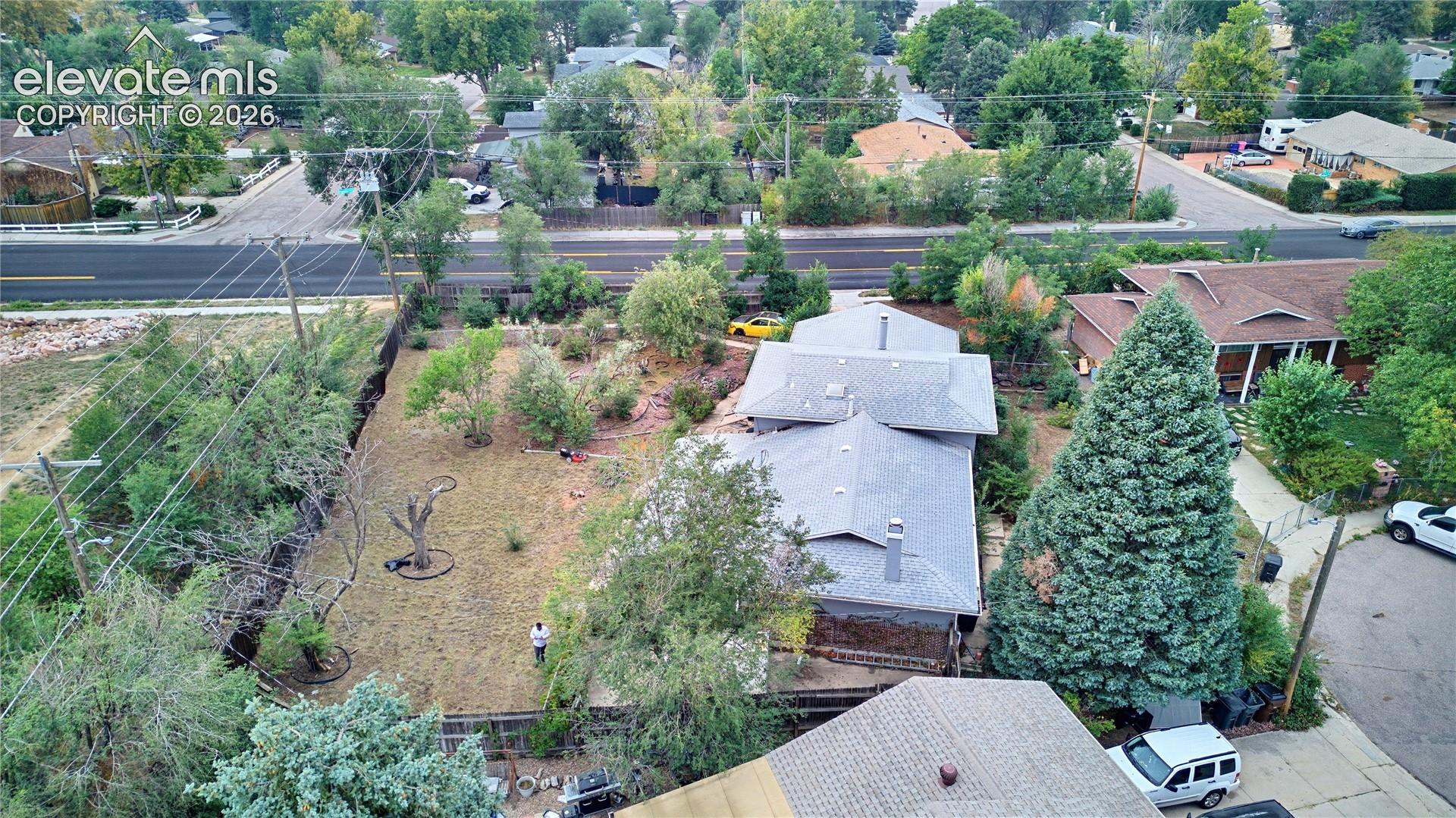 Expansive lot featuring a residential structure with multiple gables, surrounded by mature trees and landscaping