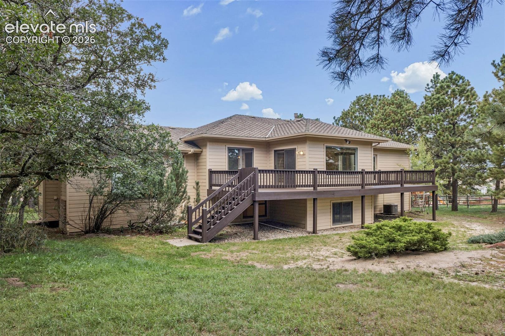 Expansive rear deck with dark wood railing and stairs