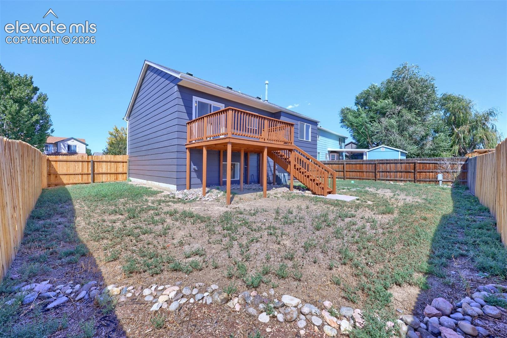Expansive backyard with a wood privacy fence, multi-level wood deck, and walk-out access