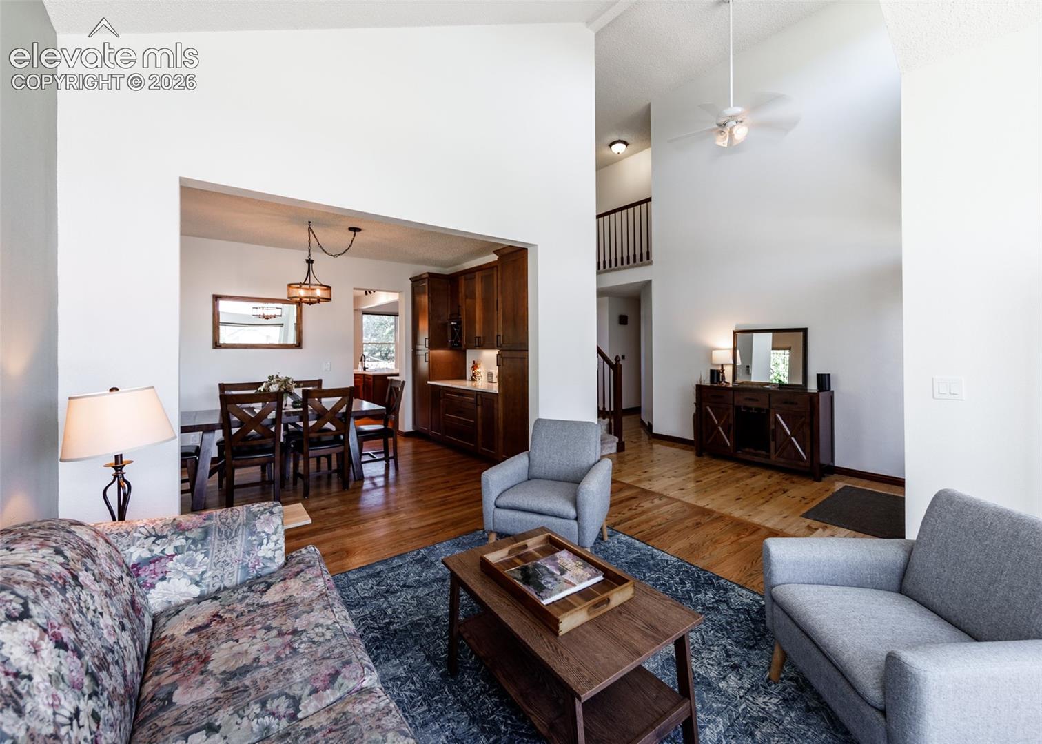 Vaulted ceilings with a ceiling fan, wood-finish flooring, and a dining area with a chandelier