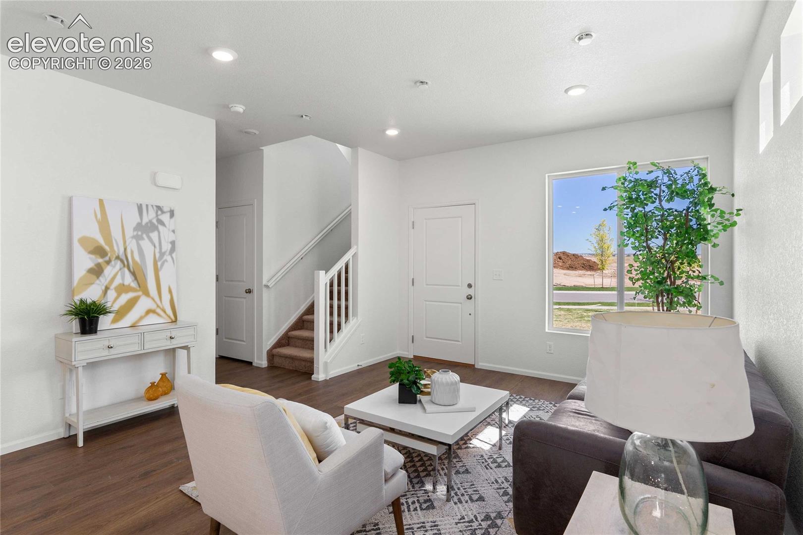 Open-concept living area with wood-finish flooring, recessed lighting, and a prominent window
*photos  of a model home*