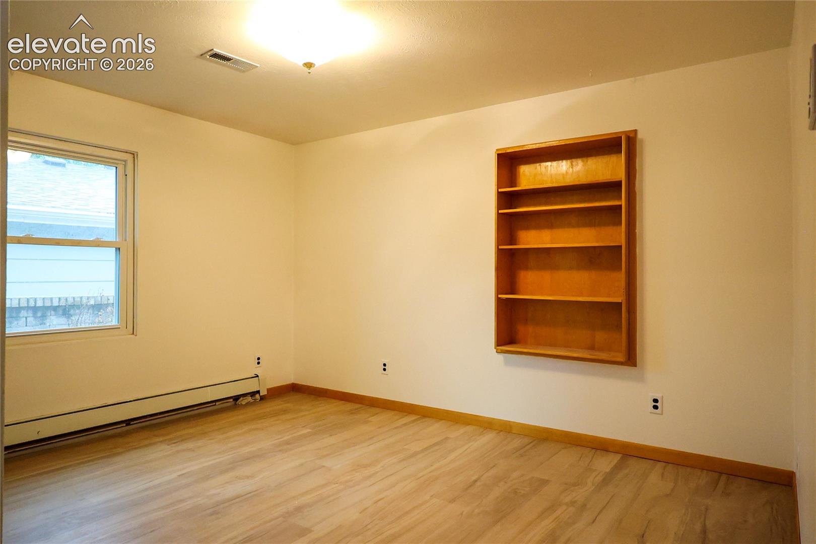 Bedroom 3 Wood-finish flooring, built-in shelving, and a double-pane window