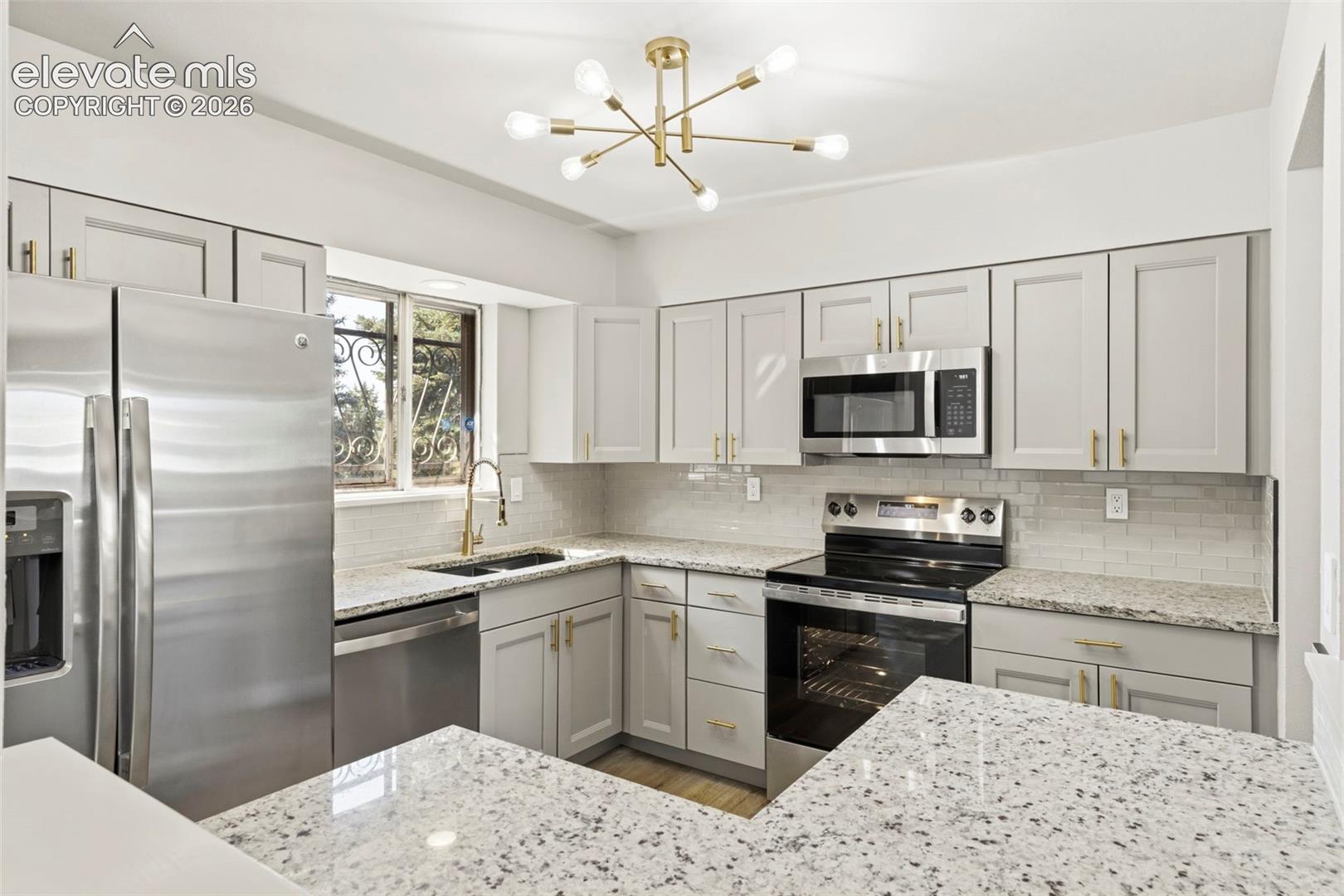 Kitchen featuring gray cabinetry, stainless steel appliances, granite countertops, and a glass subway tile backsplash