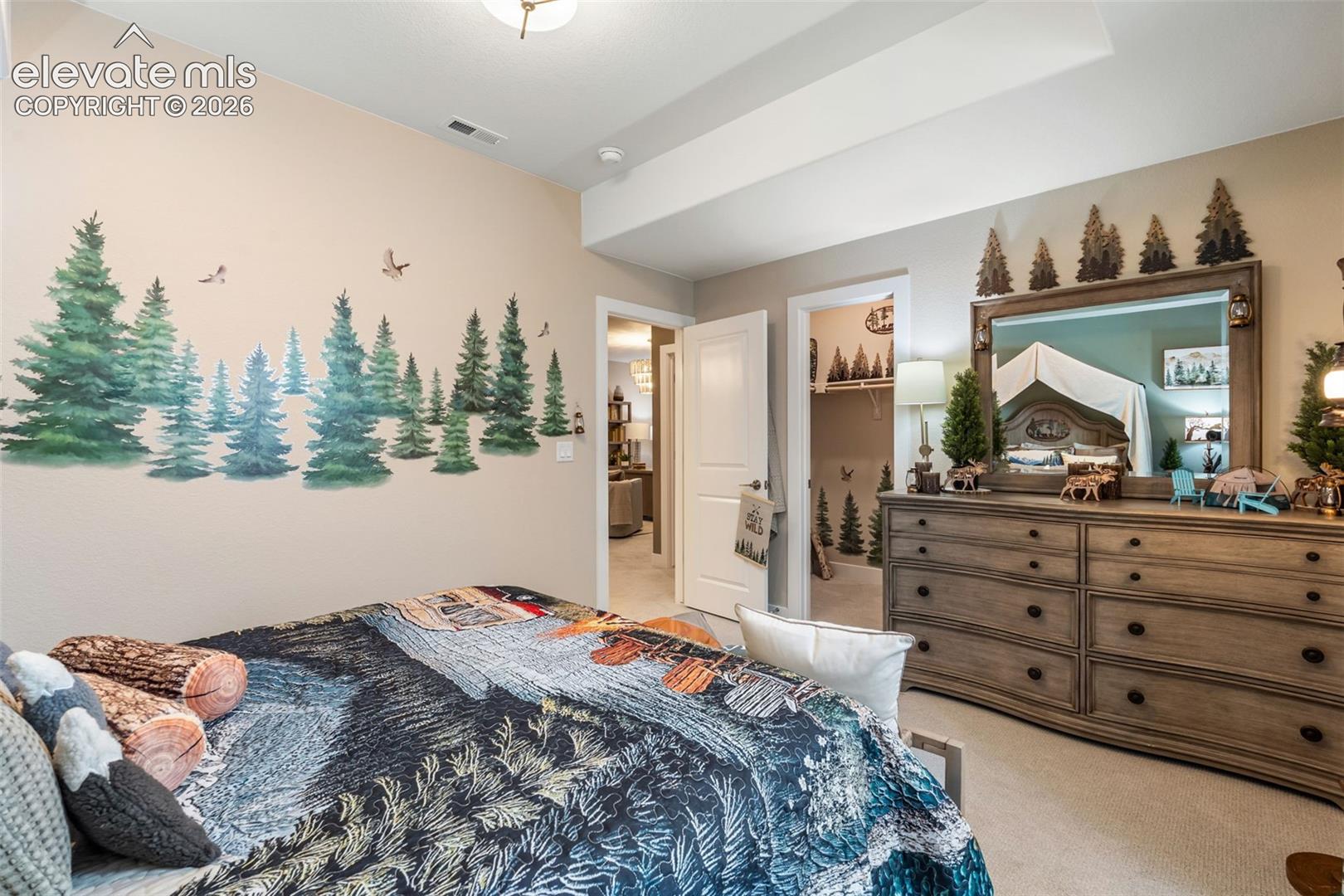 Tray ceiling with recessed lighting, neutral wall-to-wall carpeting, and a walk-in closet featuring built-in shelving