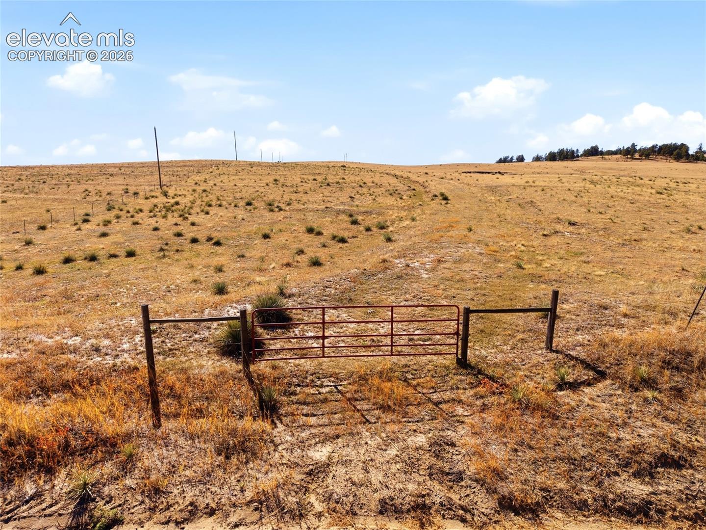 Expansive acreage featuring rolling terrain and a metal perimeter gate