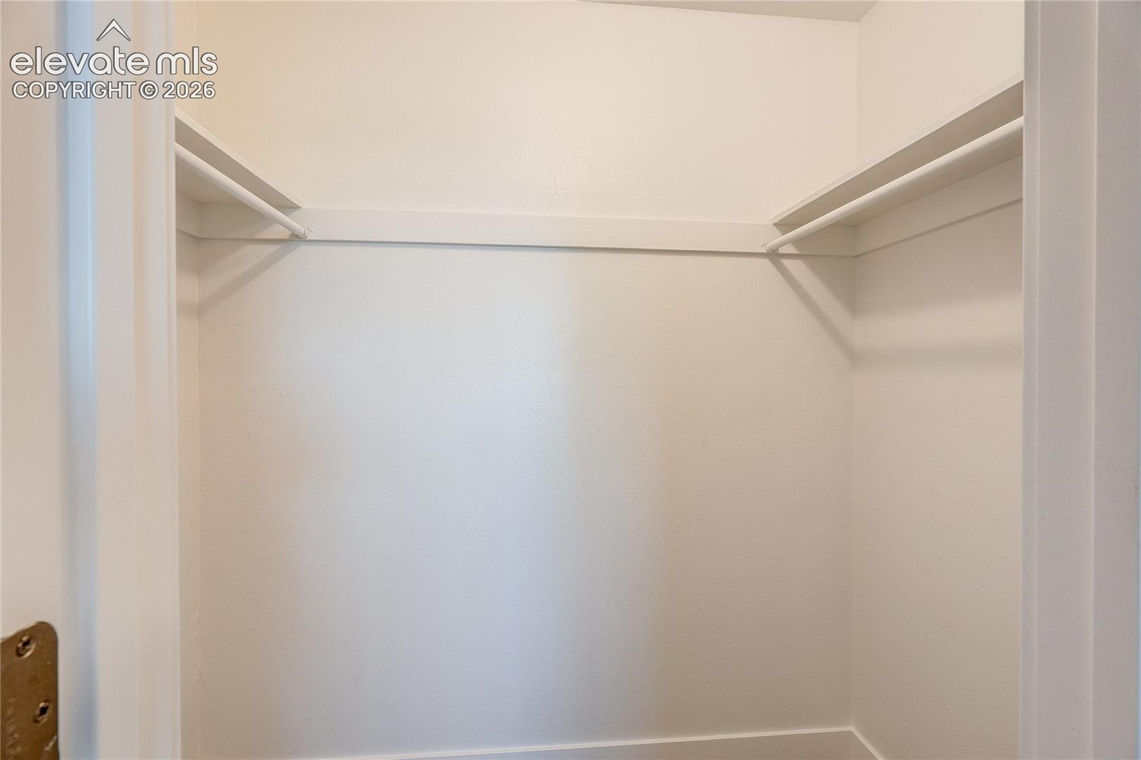 Reach-in closet featuring white-painted shelving and integrated hanging rods