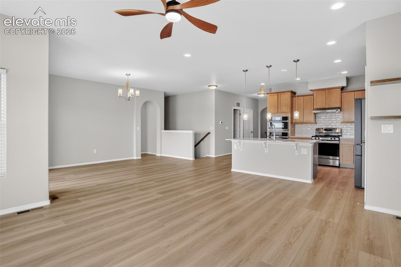 Open-concept living space featuring wood-finish flooring, recessed lighting, and a ceiling fan