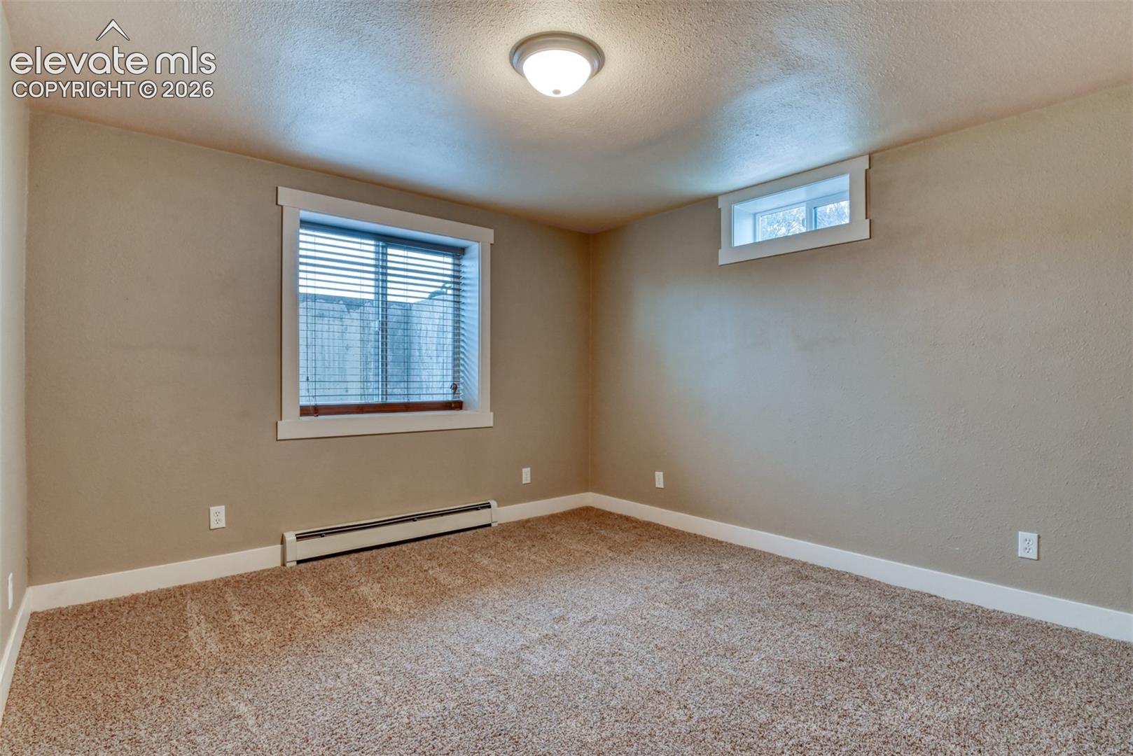 Unfurnished room with a baseboard radiator, light carpet, and a textured ceiling
