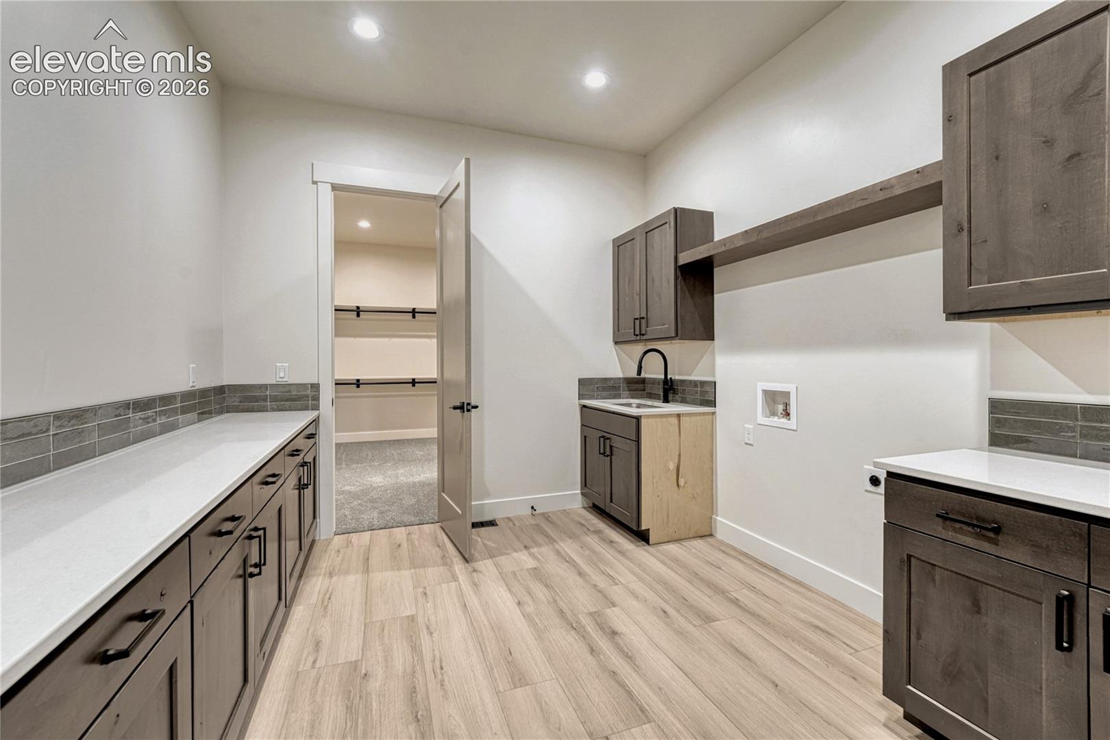 Access this laundry room from the primary bedroom's walk-in closet or the mud room. 